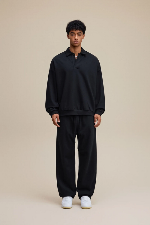 Person wearing a black outfit with white shoes on a beige background