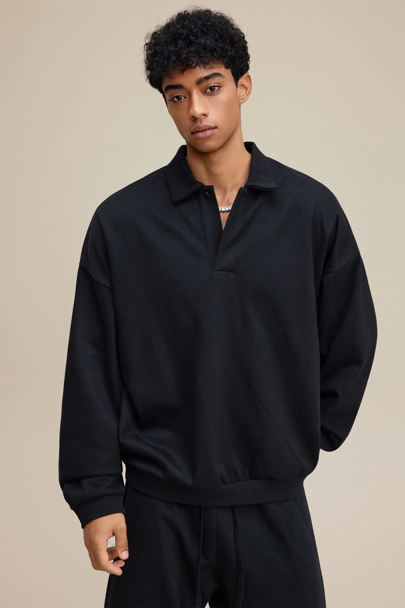 Person wearing a black outfit against a beige background