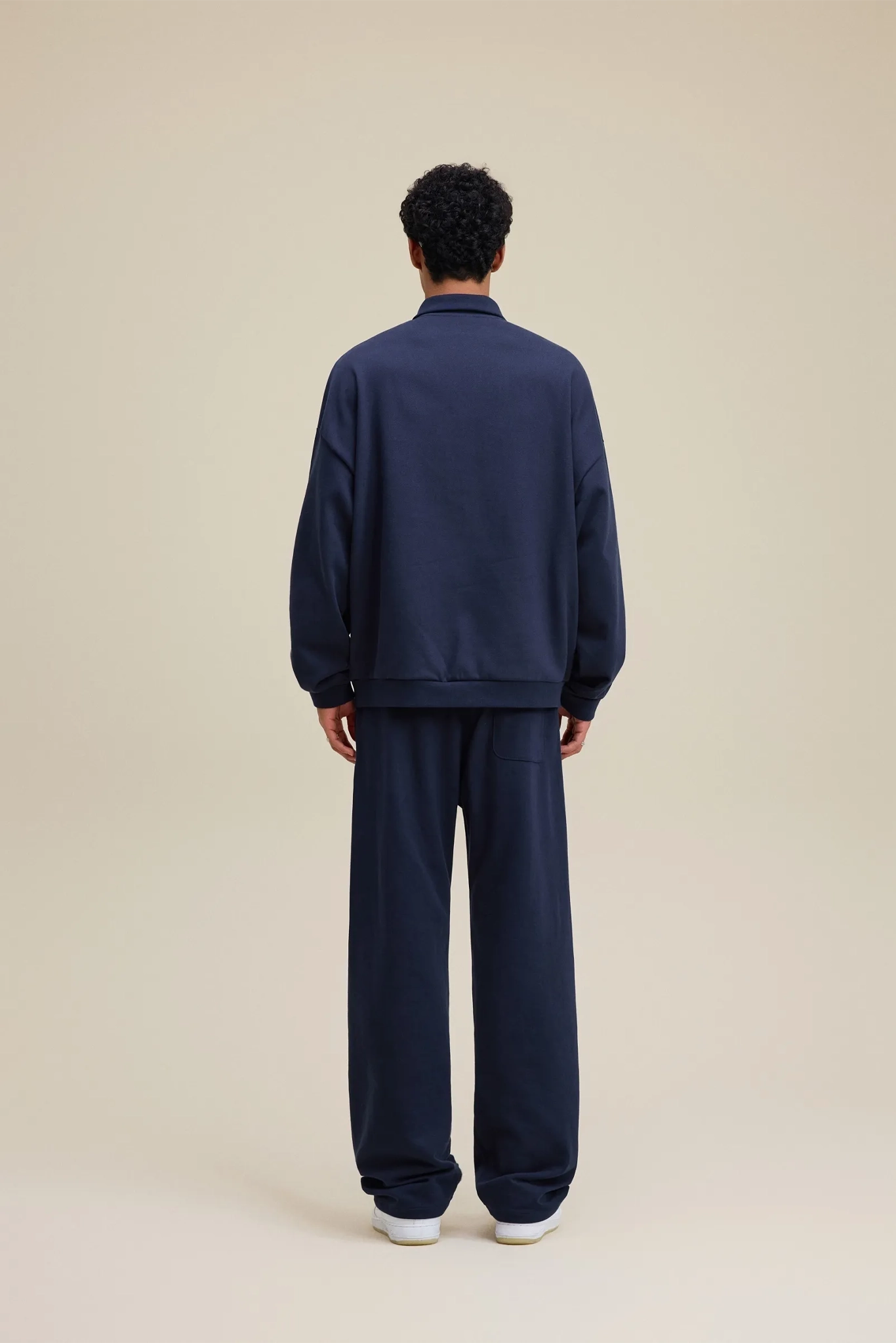 Person wearing a navy tracksuit on a beige background