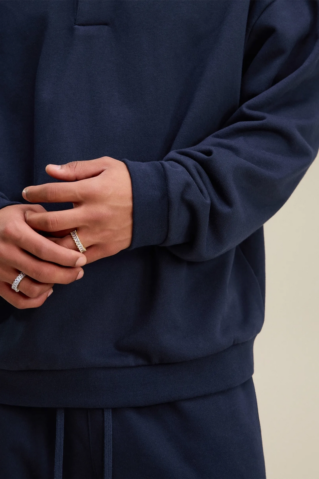 Person wearing a navy blue outfit with visible jewelry on a neutral background