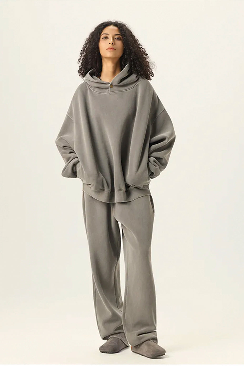 Person wearing a gray hoodie and pants on a white background