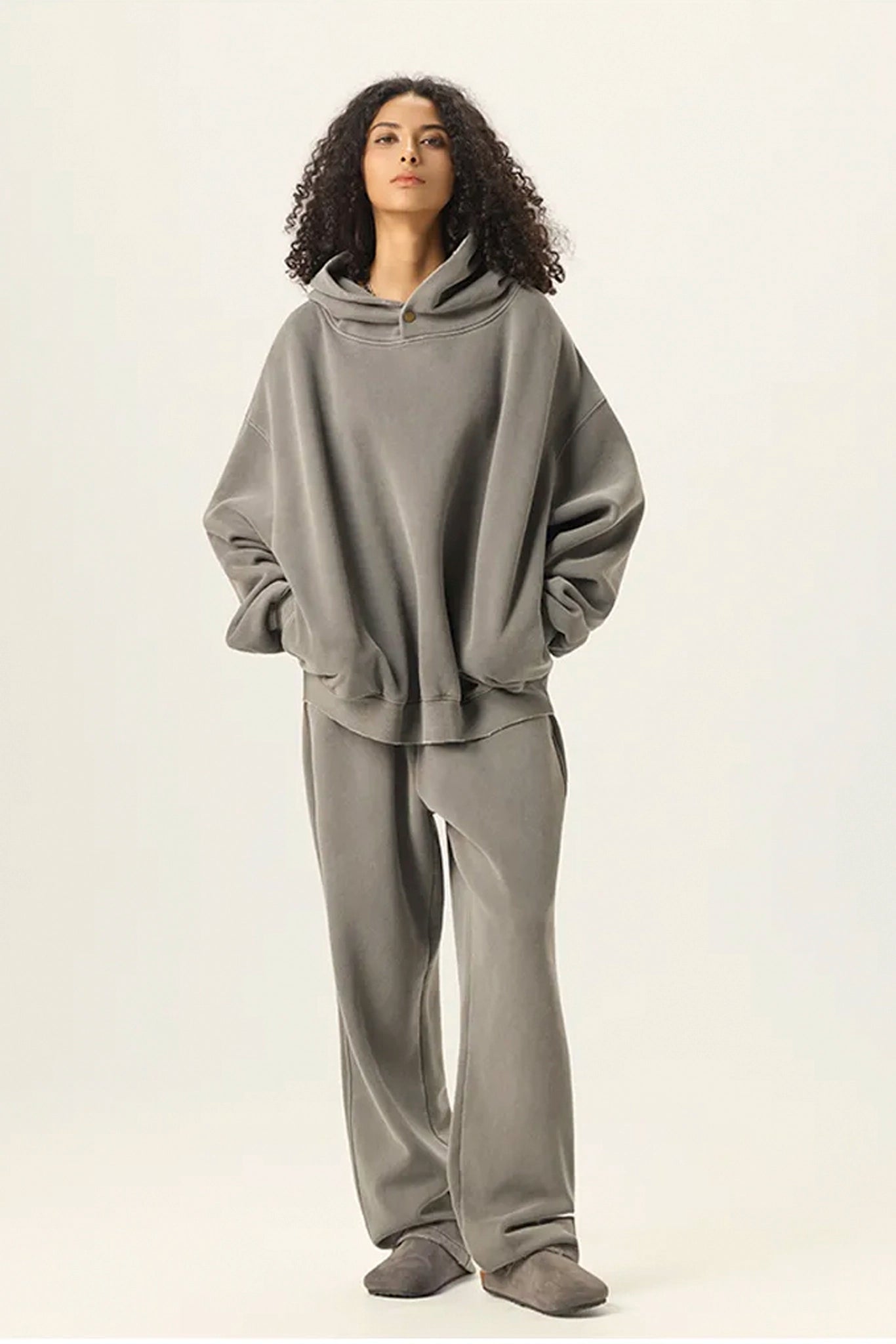 Person wearing a gray hoodie and pants on a white background