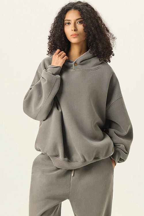 Woman wearing a gray hoodie and pants on a beige background