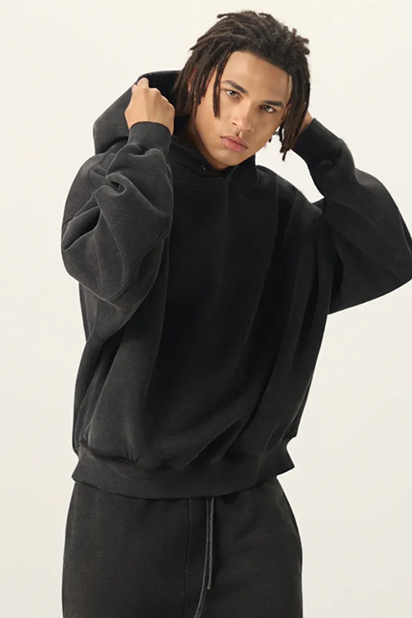 Person wearing a black hoodie and pants on a plain background