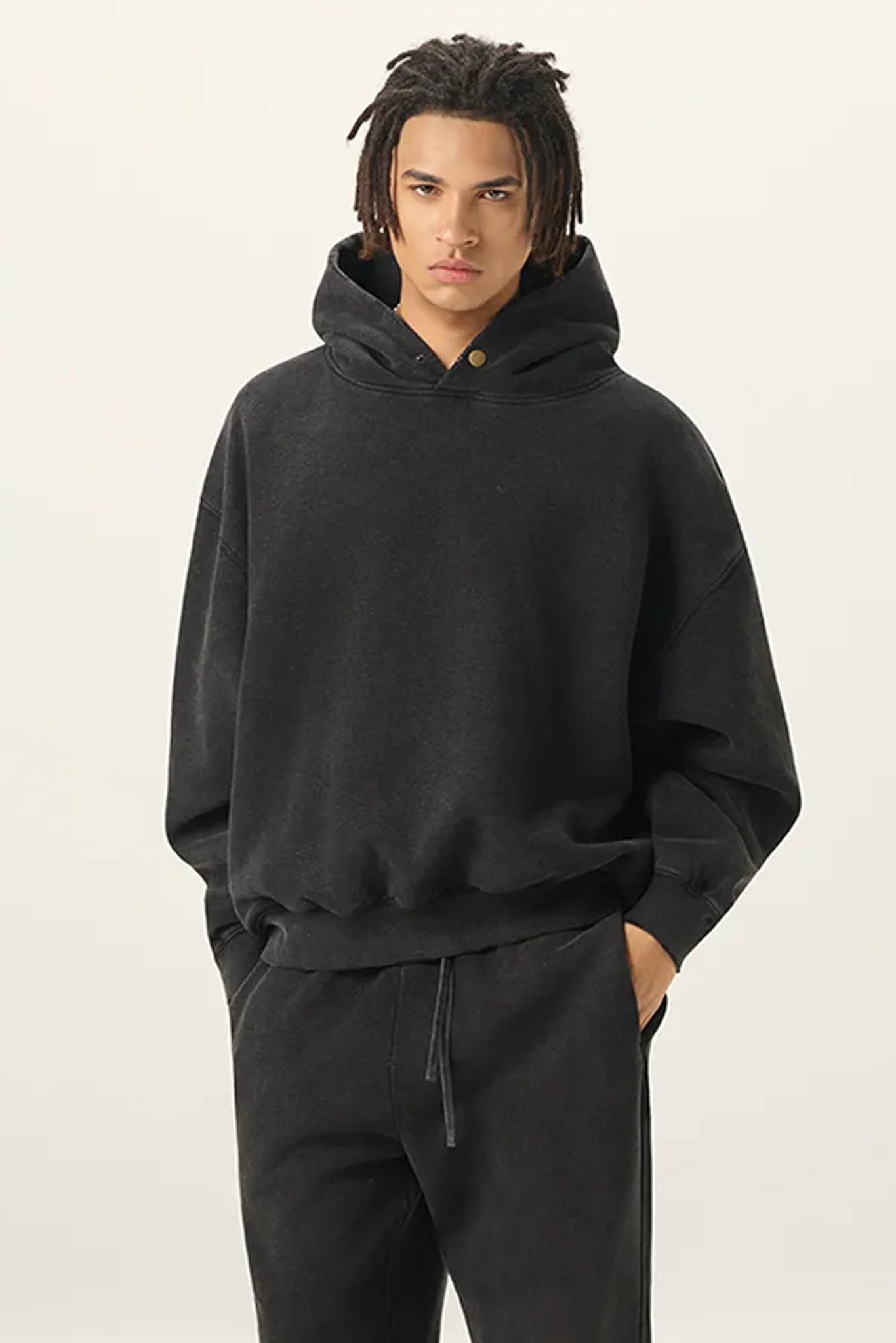 Person wearing a black hoodie and pants on a plain background