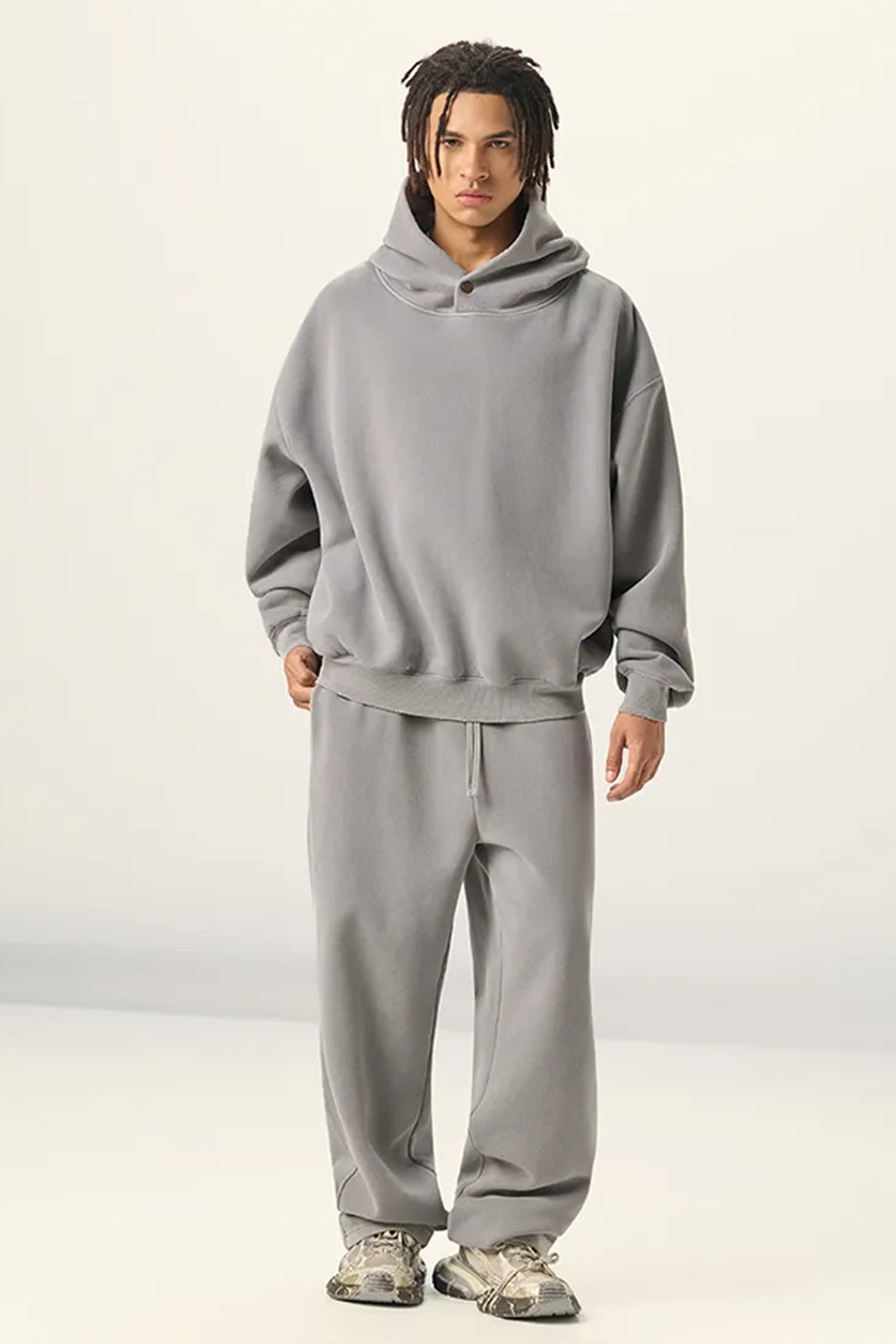 Person wearing a gray hoodie and pants on a white background