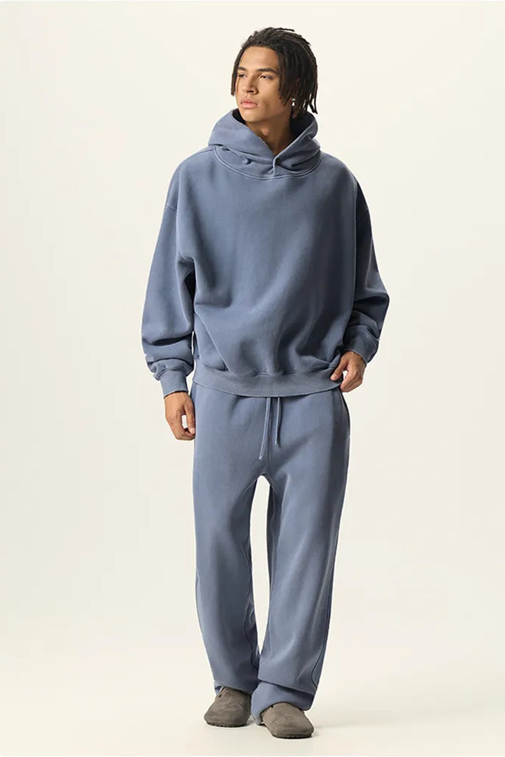Person wearing a blue hoodie and pants on a plain background