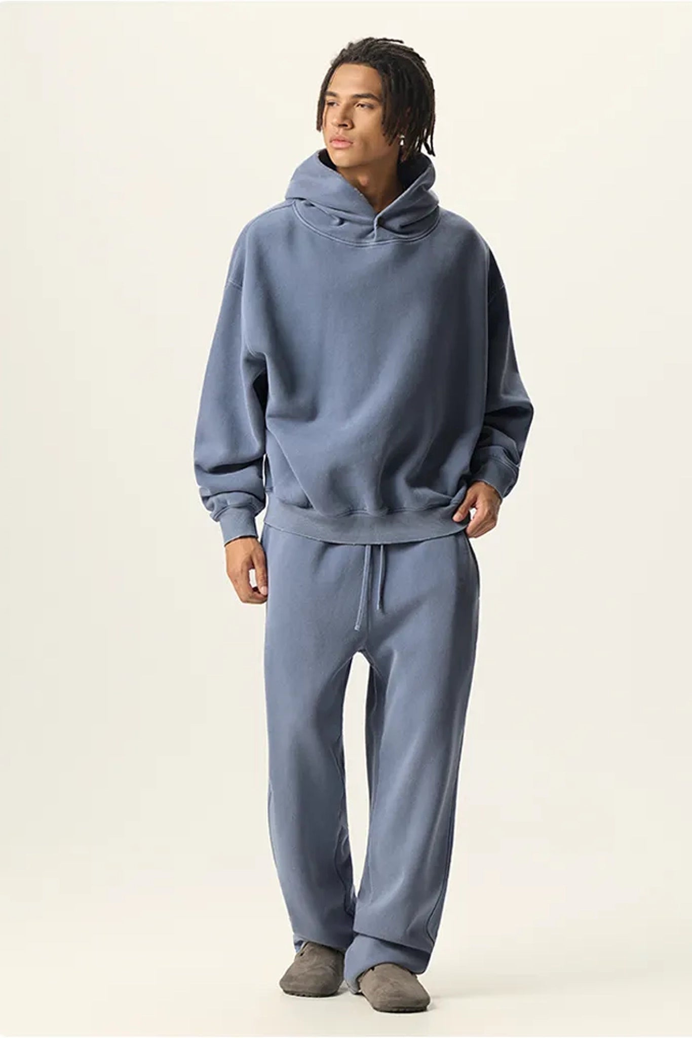 Person wearing a blue hoodie and pants on a plain background