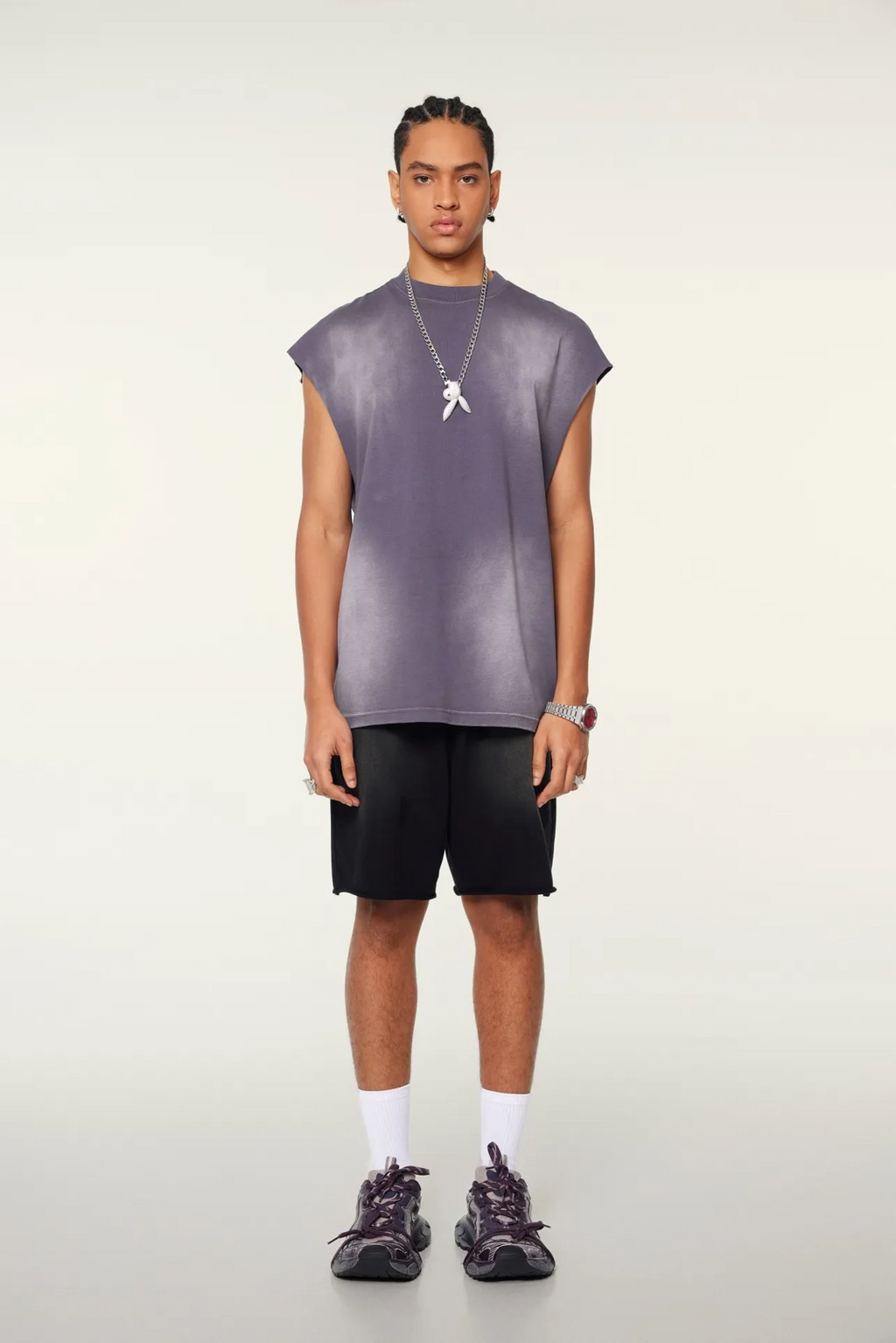 Person wearing a sleeveless purple top and black shorts on a white background
