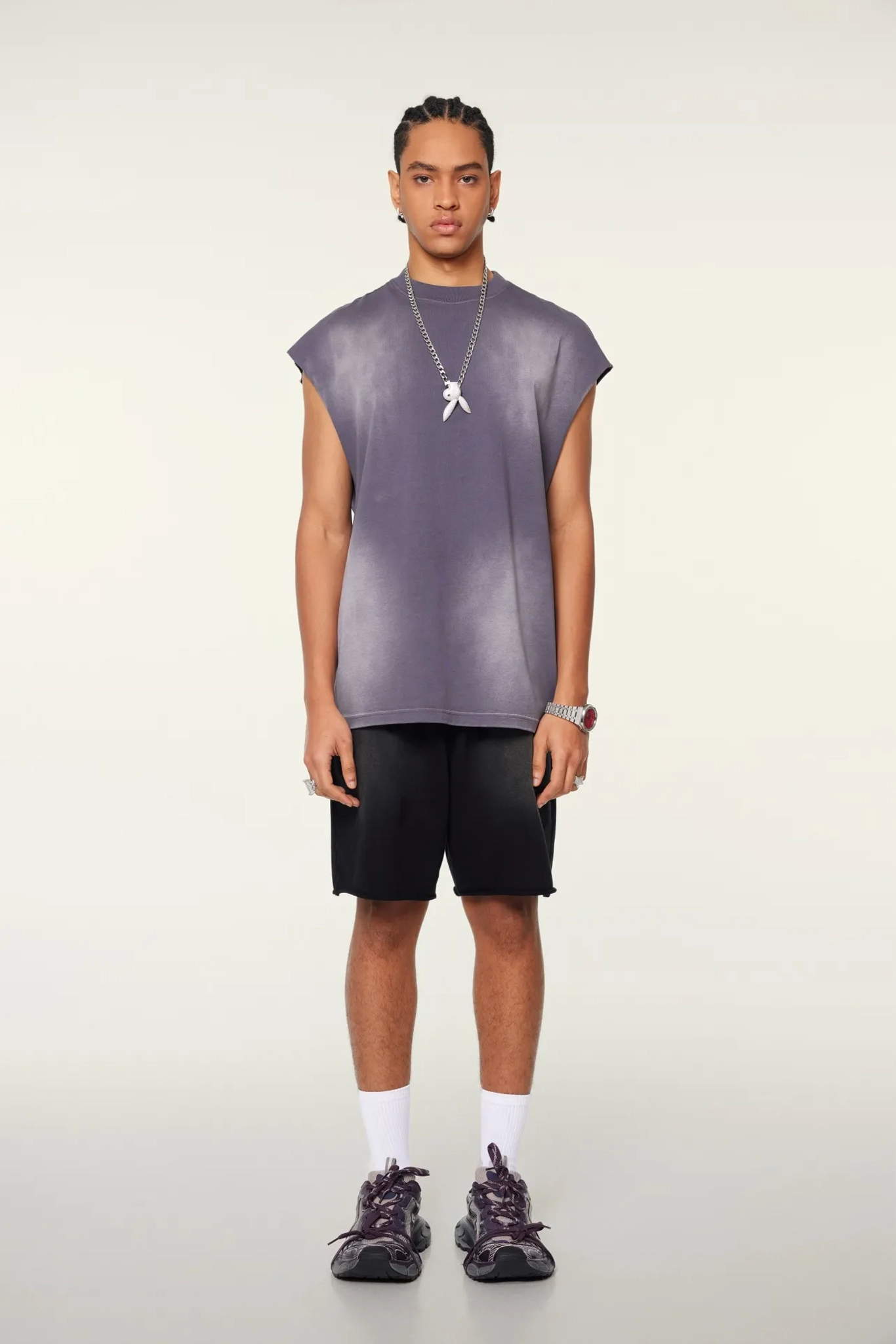 Person wearing a sleeveless purple top and black shorts on a white background