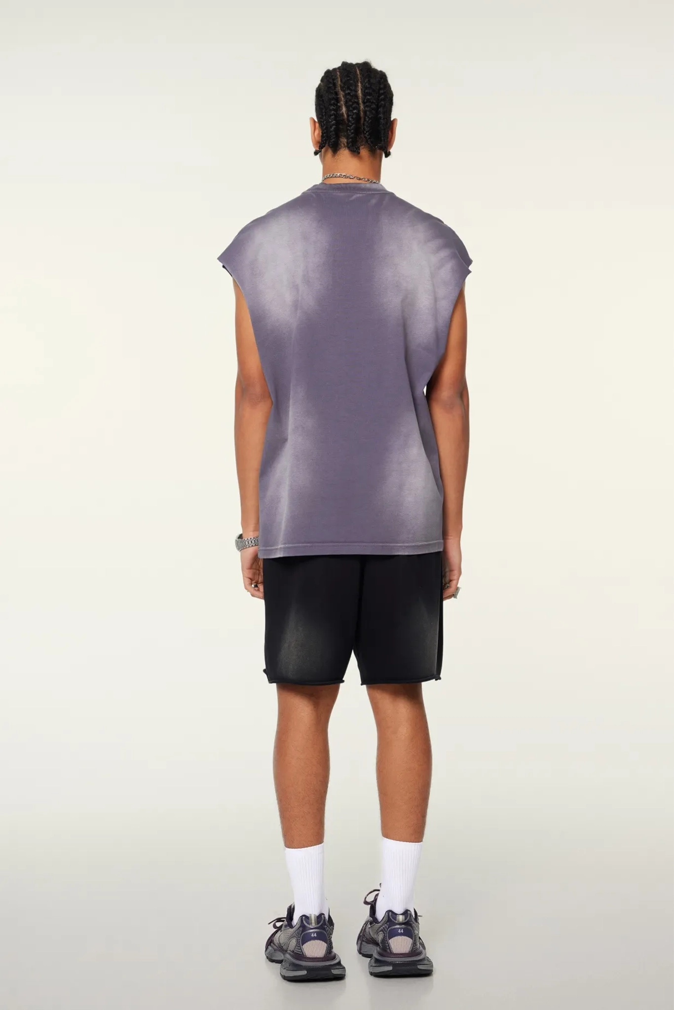Person wearing a sleeveless purple shirt and black shorts on a white background