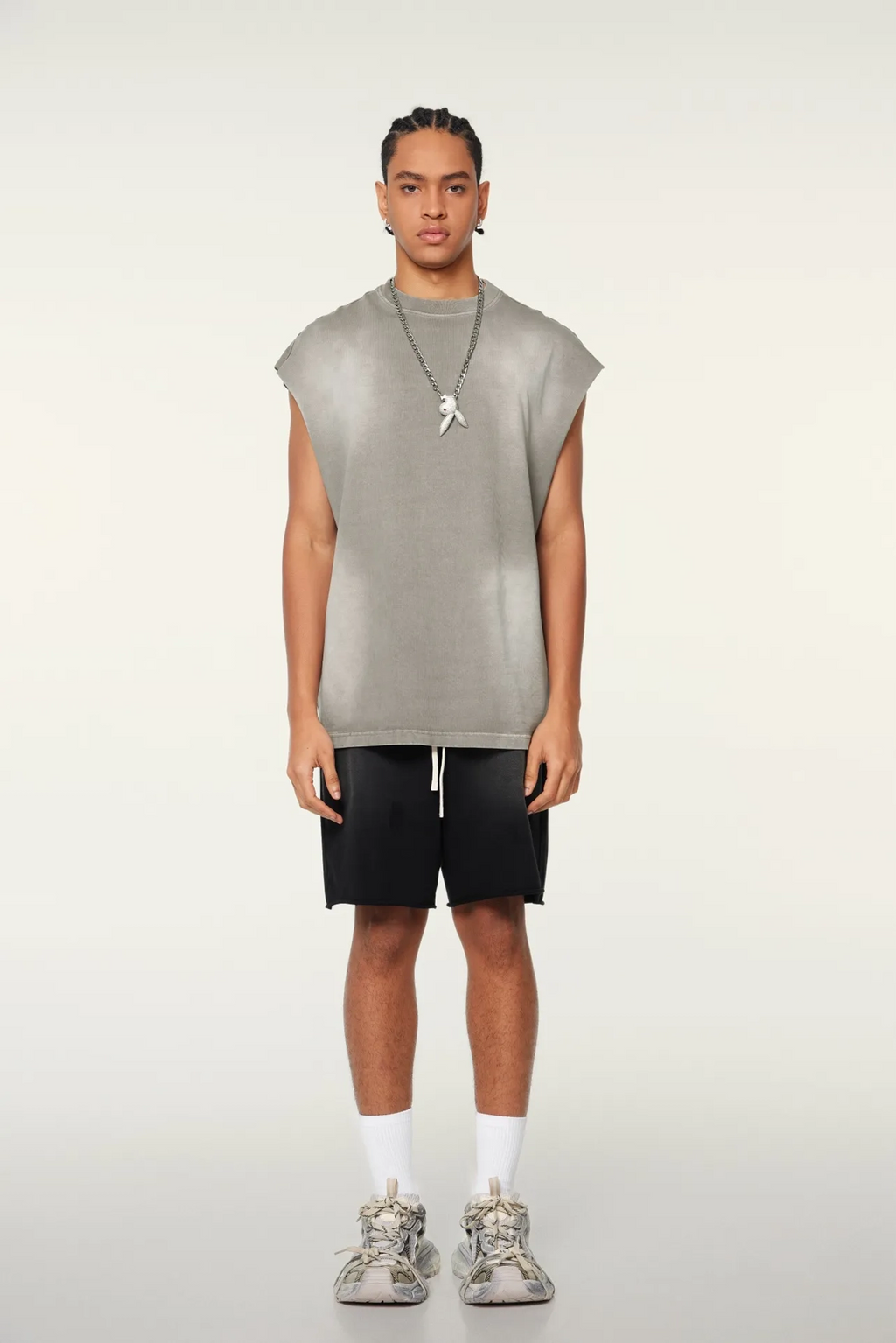 Person wearing a sleeveless gray top and black shorts on a white background