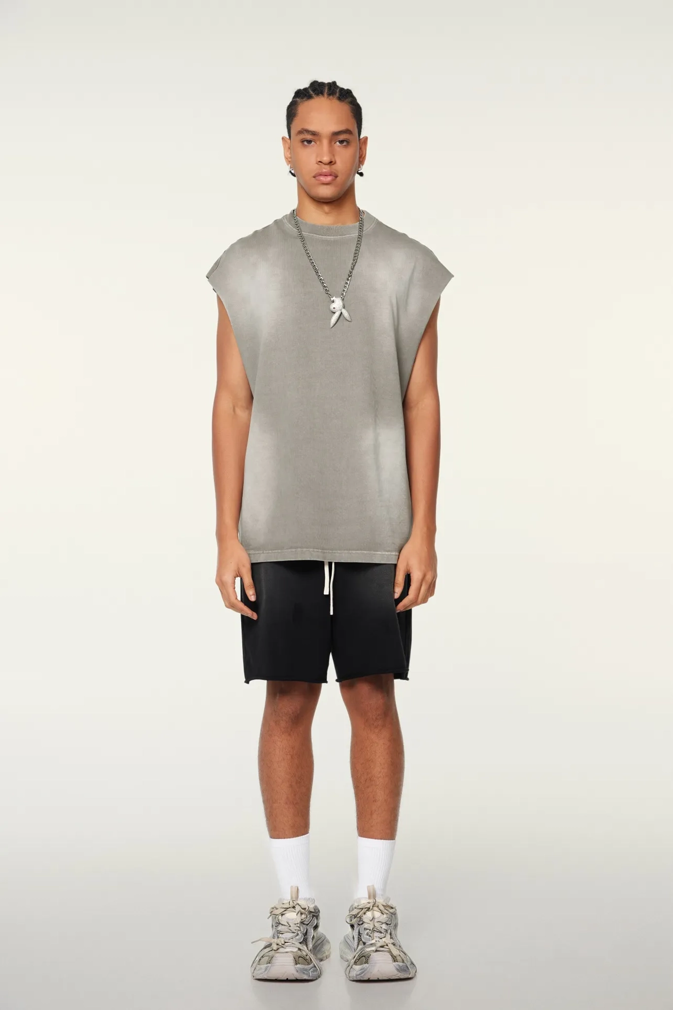 Person wearing a sleeveless gray top and black shorts on a white background