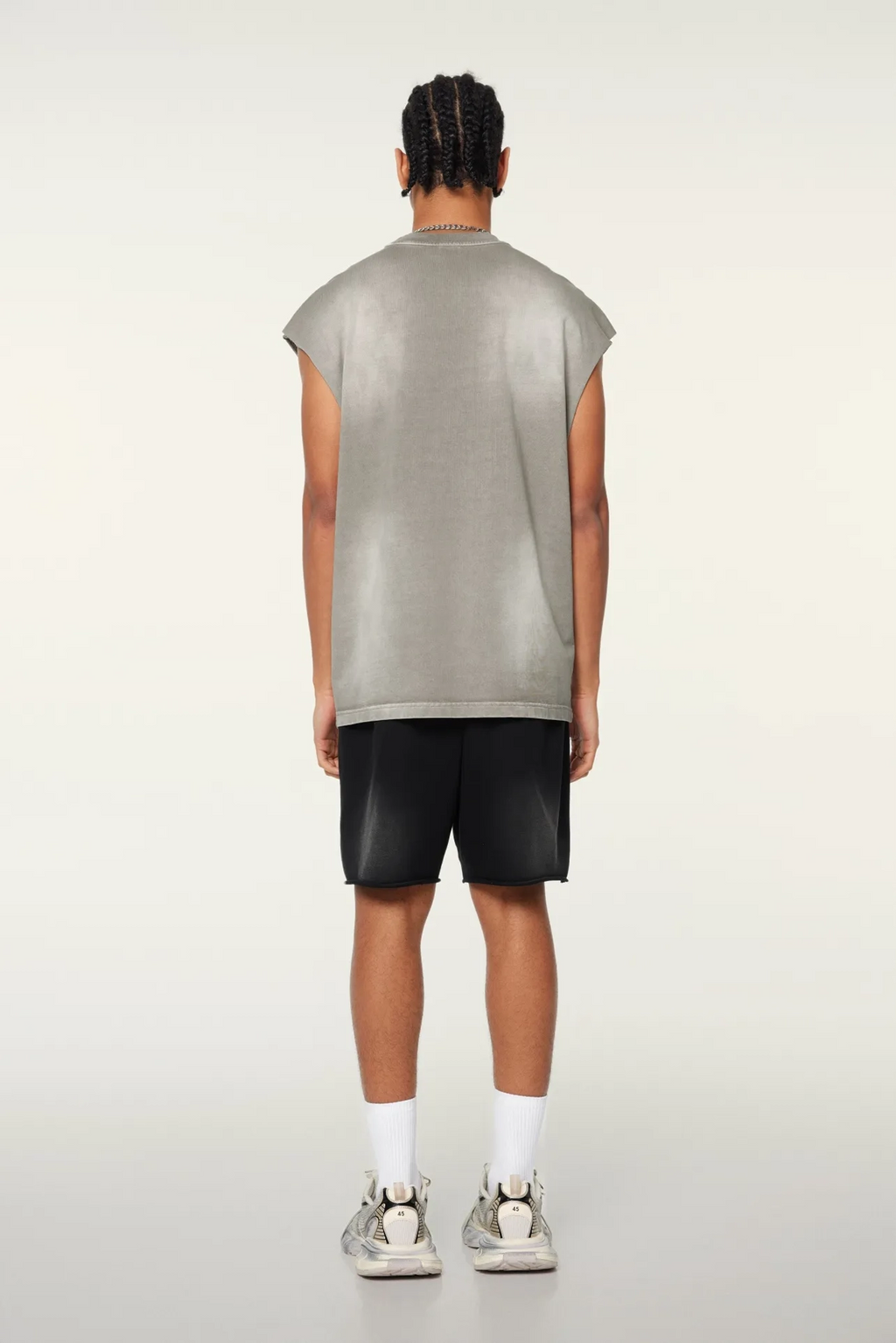 Person wearing a gray sleeveless shirt and black shorts on a white background