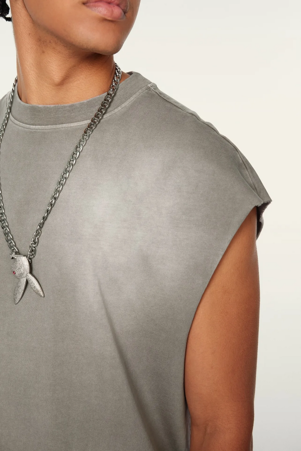 Person wearing a gray sleeveless top with a chain necklace