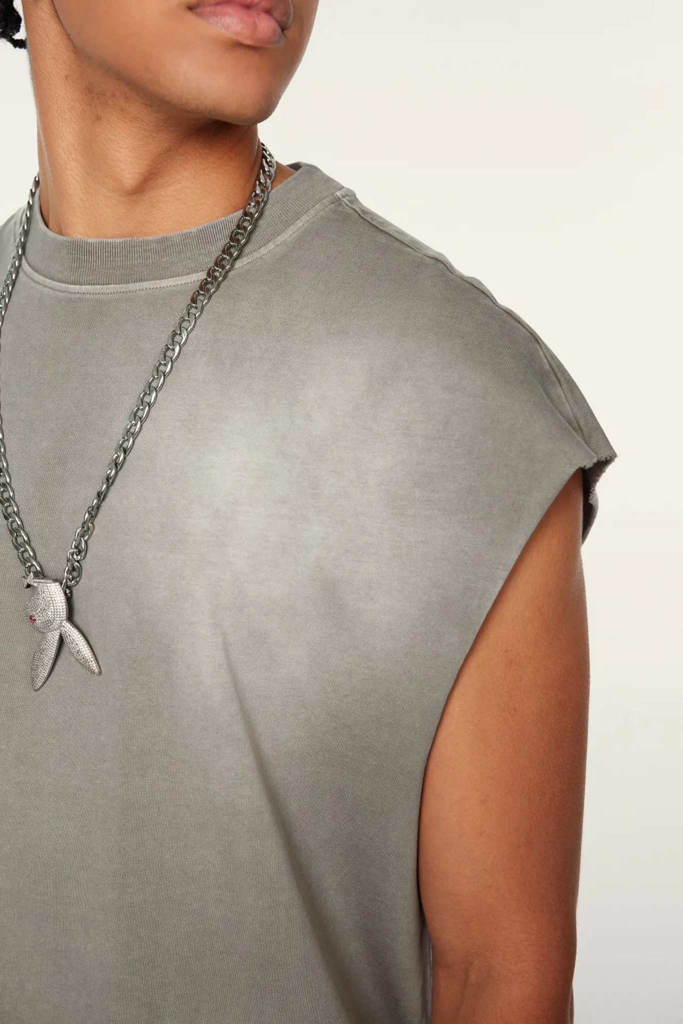 Person wearing a gray sleeveless top with a chain necklace
