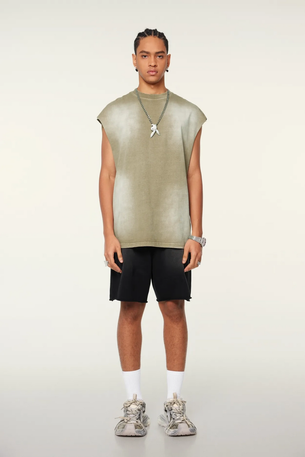 Man wearing a sleeveless green top and black shorts on a white background