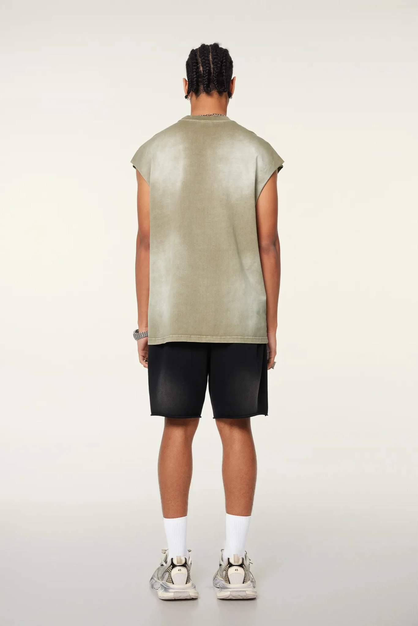 Person wearing a green sleeveless top and black shorts on a white background