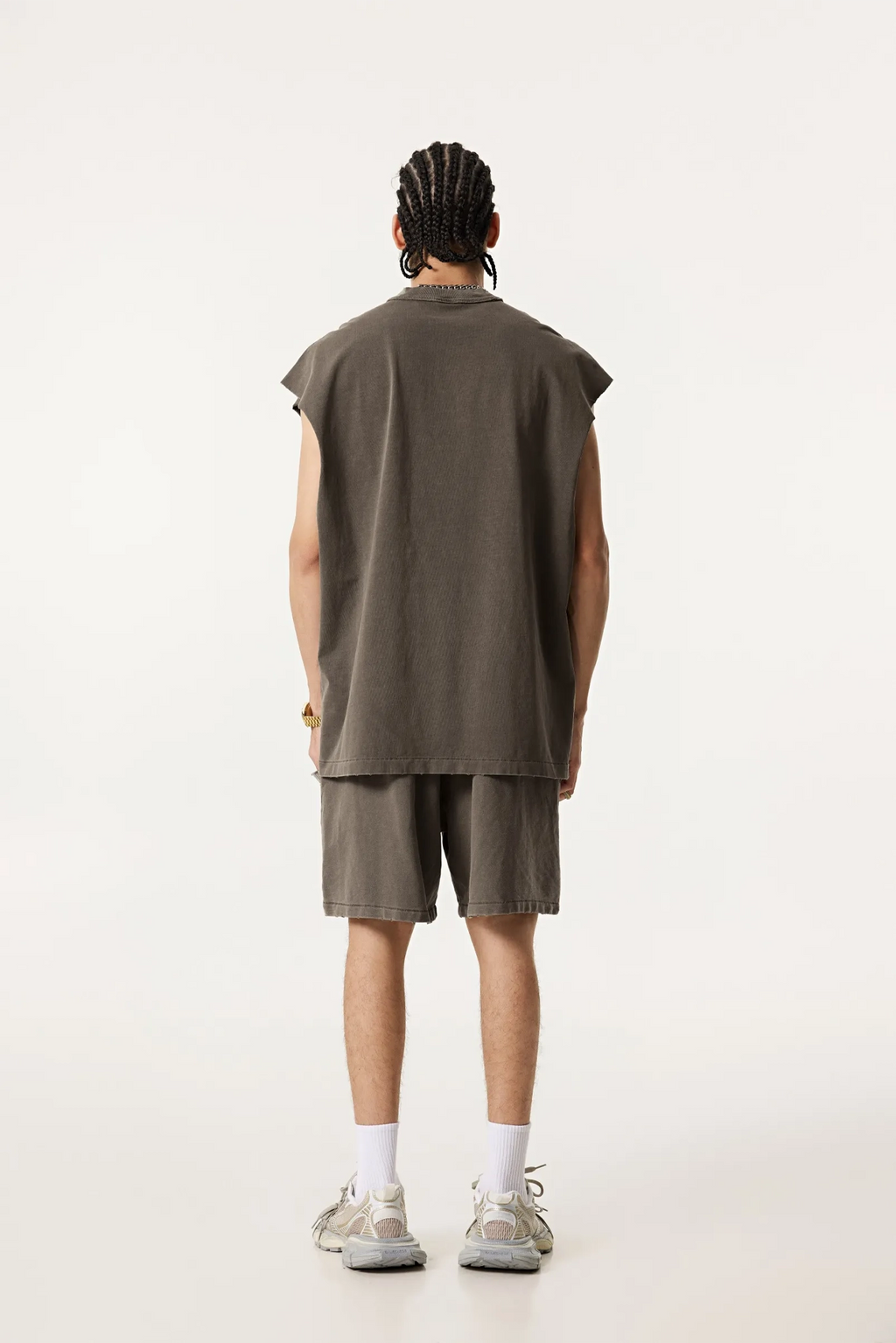 Person wearing a sleeveless green shirt and shorts on a white background