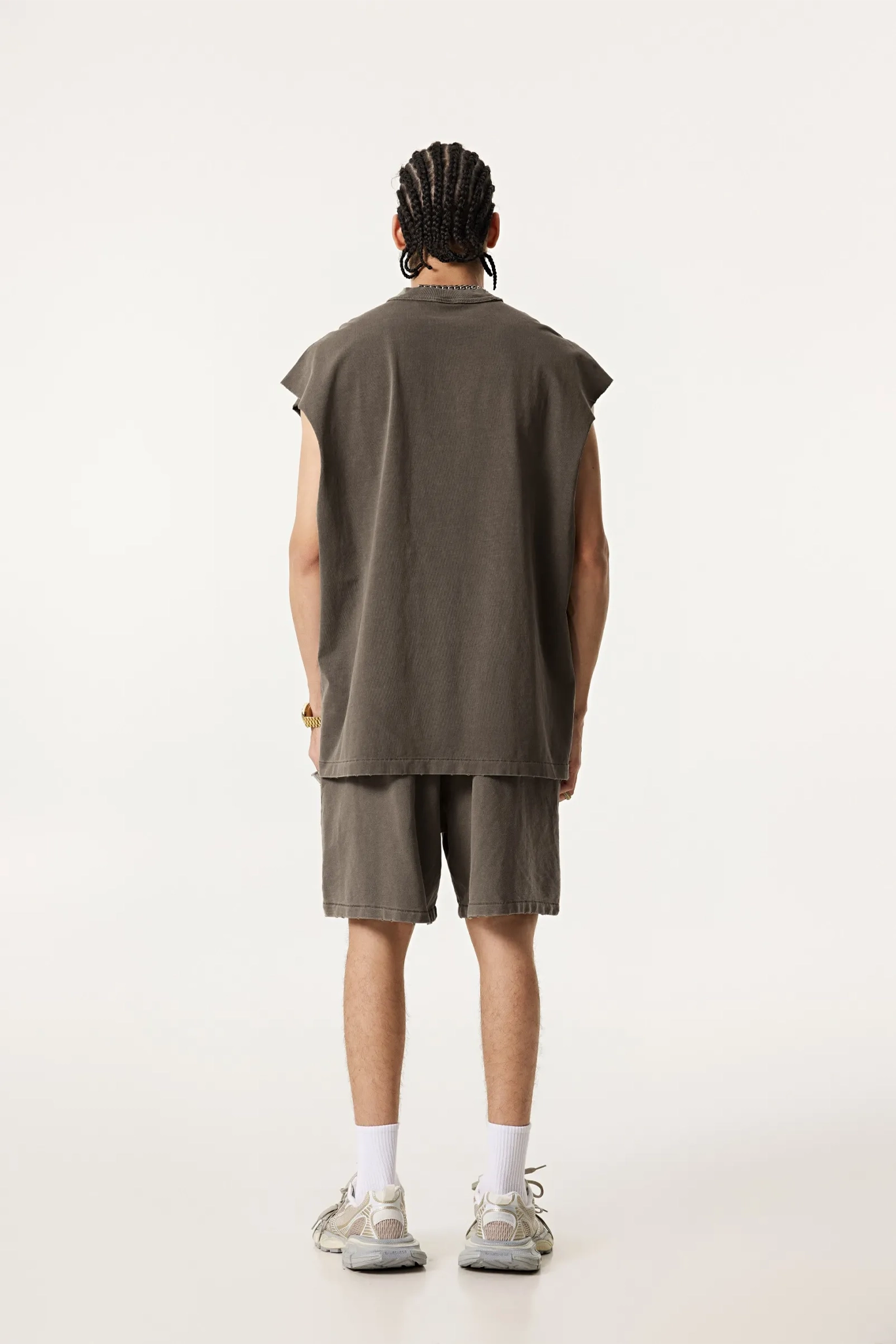 Person wearing a sleeveless green shirt and shorts on a white background