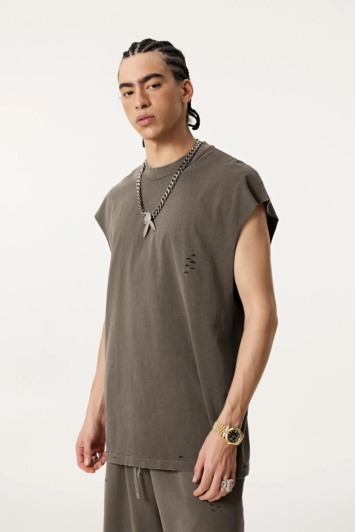 Man wearing a brown sleeveless shirt and pants on a white background