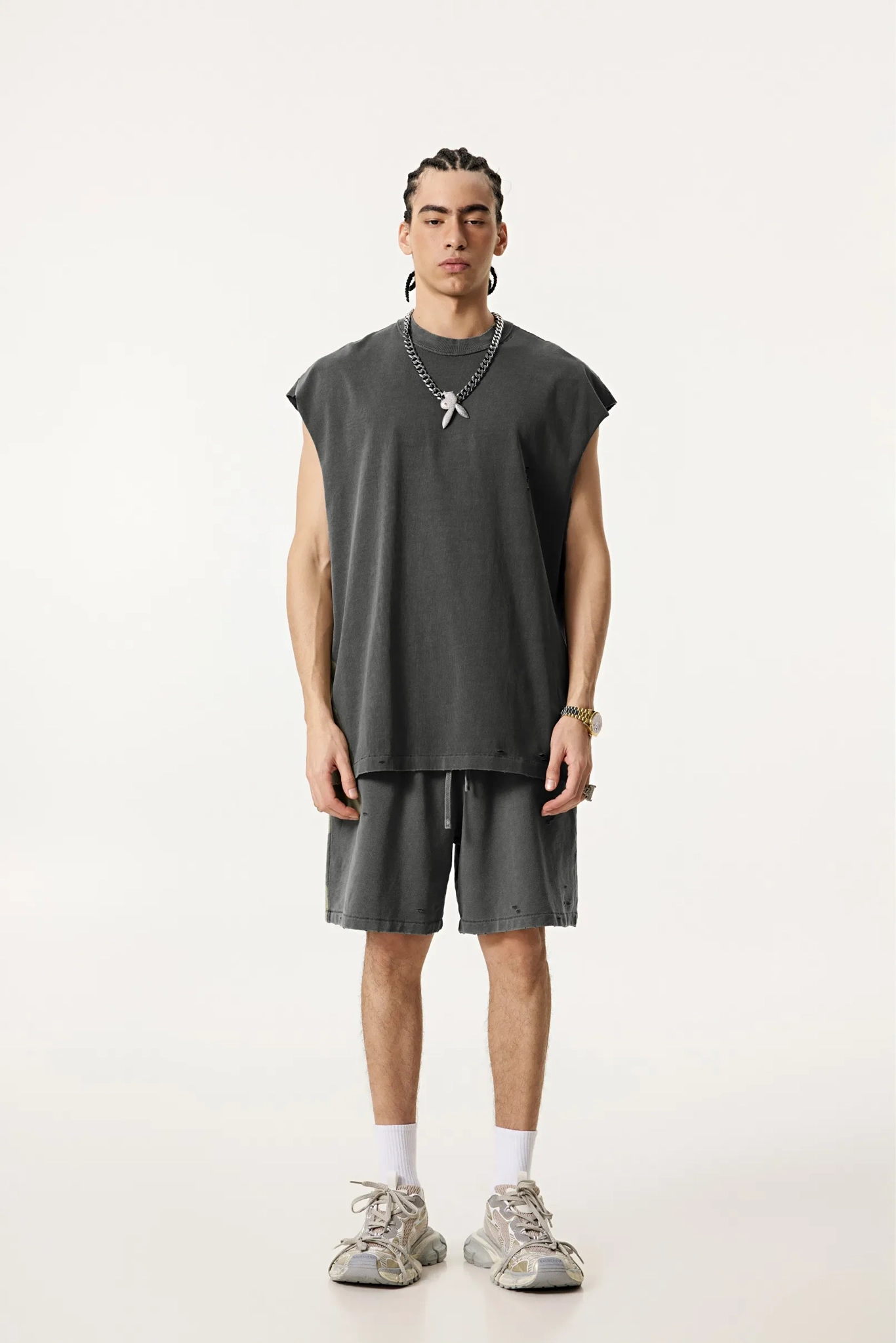 Person wearing a dark gray sleeveless top and shorts set on a white background