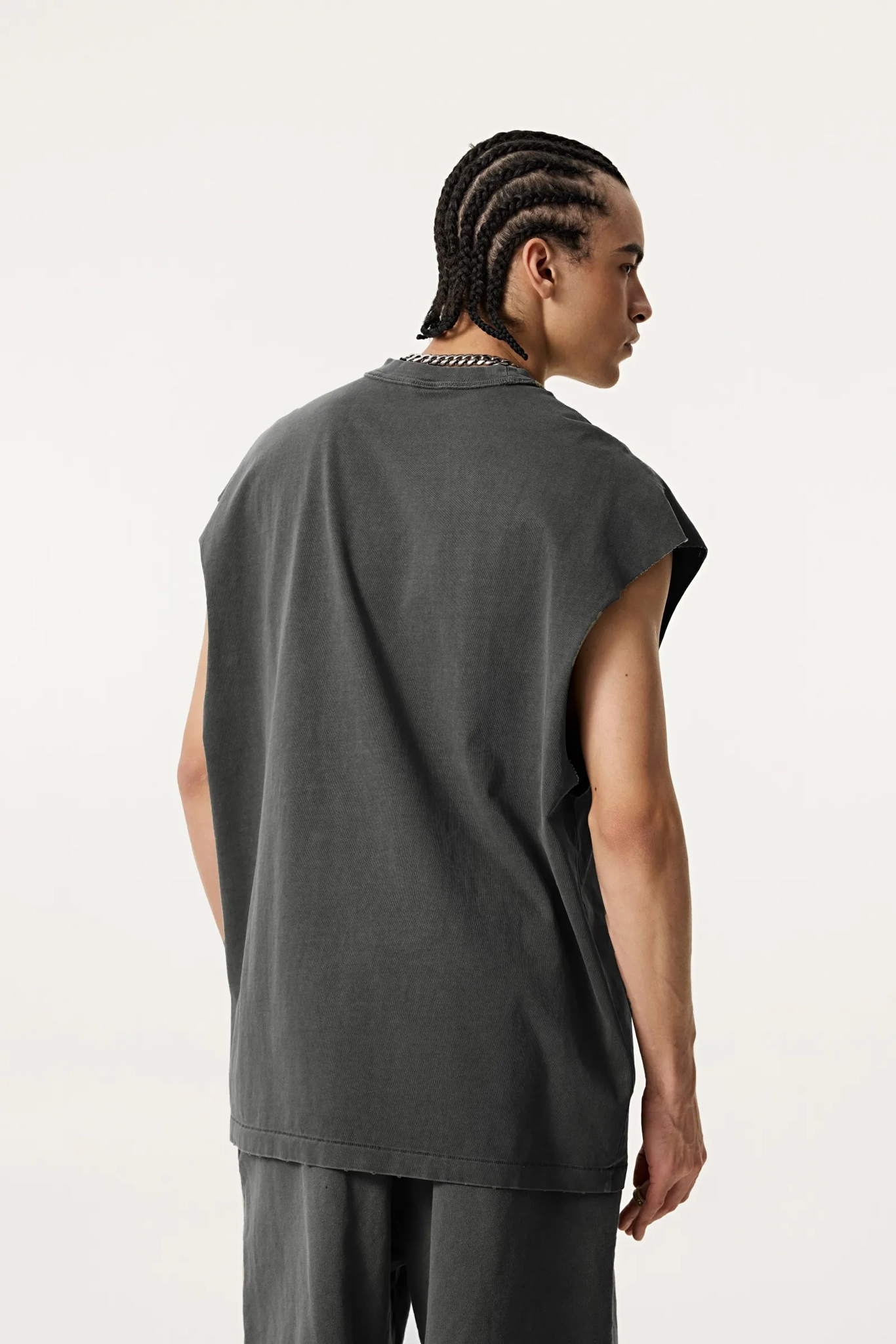 Person wearing a dark gray sleeveless top and pants on a white background