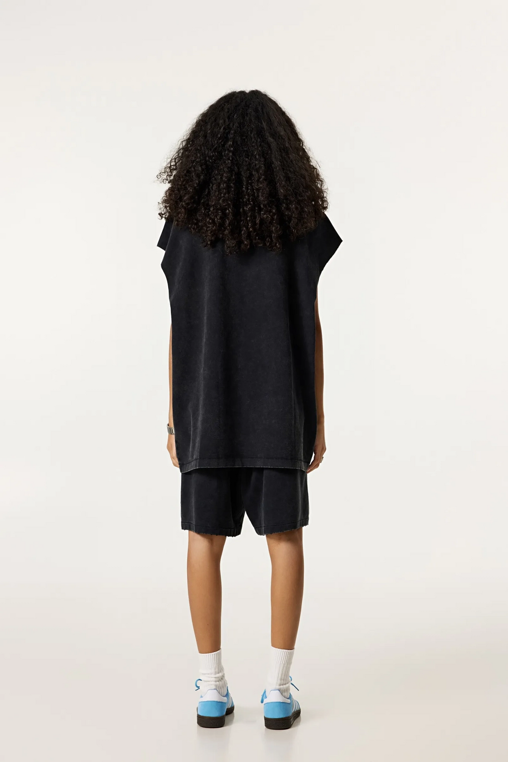 Person wearing a black sleeveless top and shorts on a white background