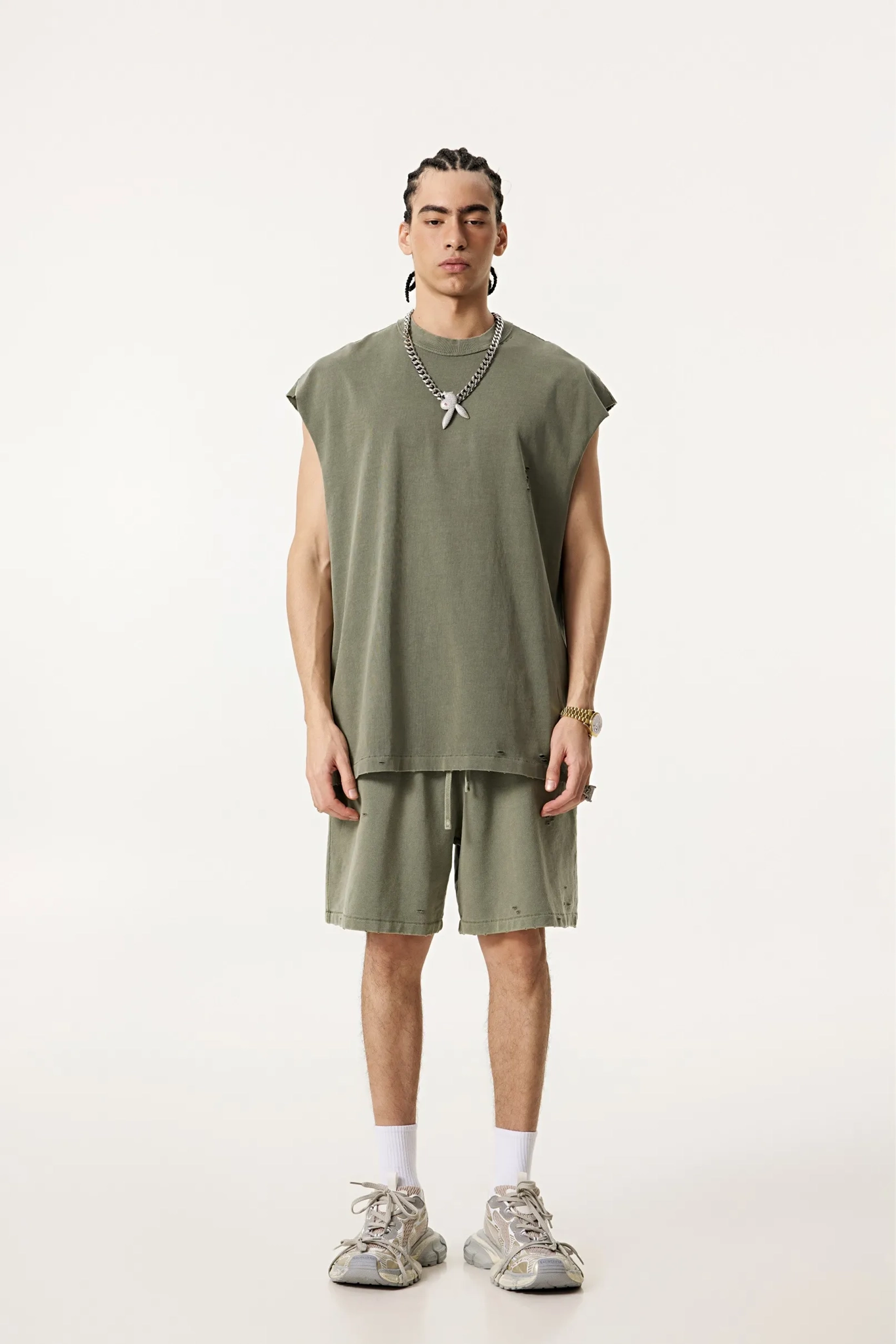 Person wearing a green sleeveless top and shorts set on a white background