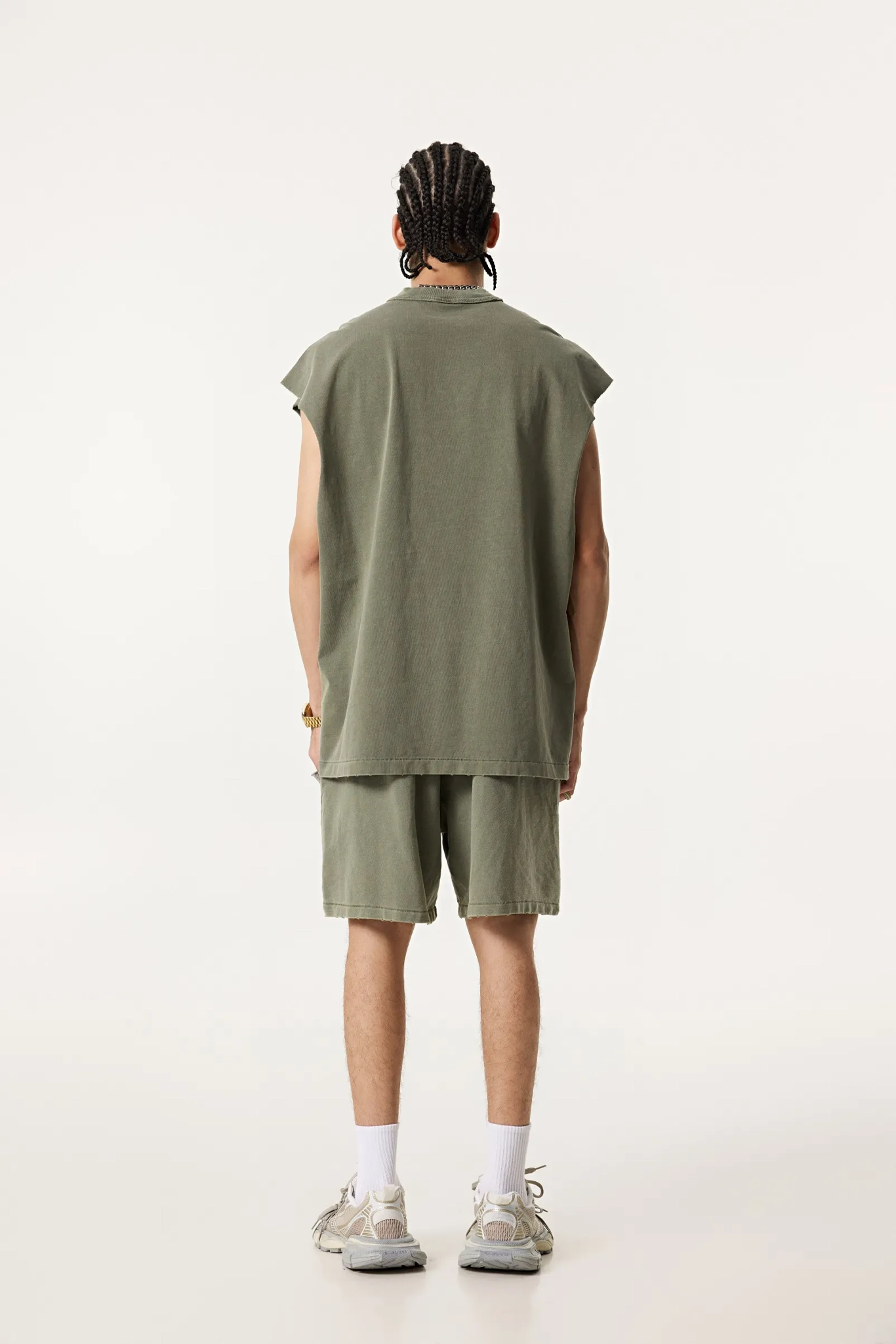 Person wearing a sleeveless green top and shorts set on a white background