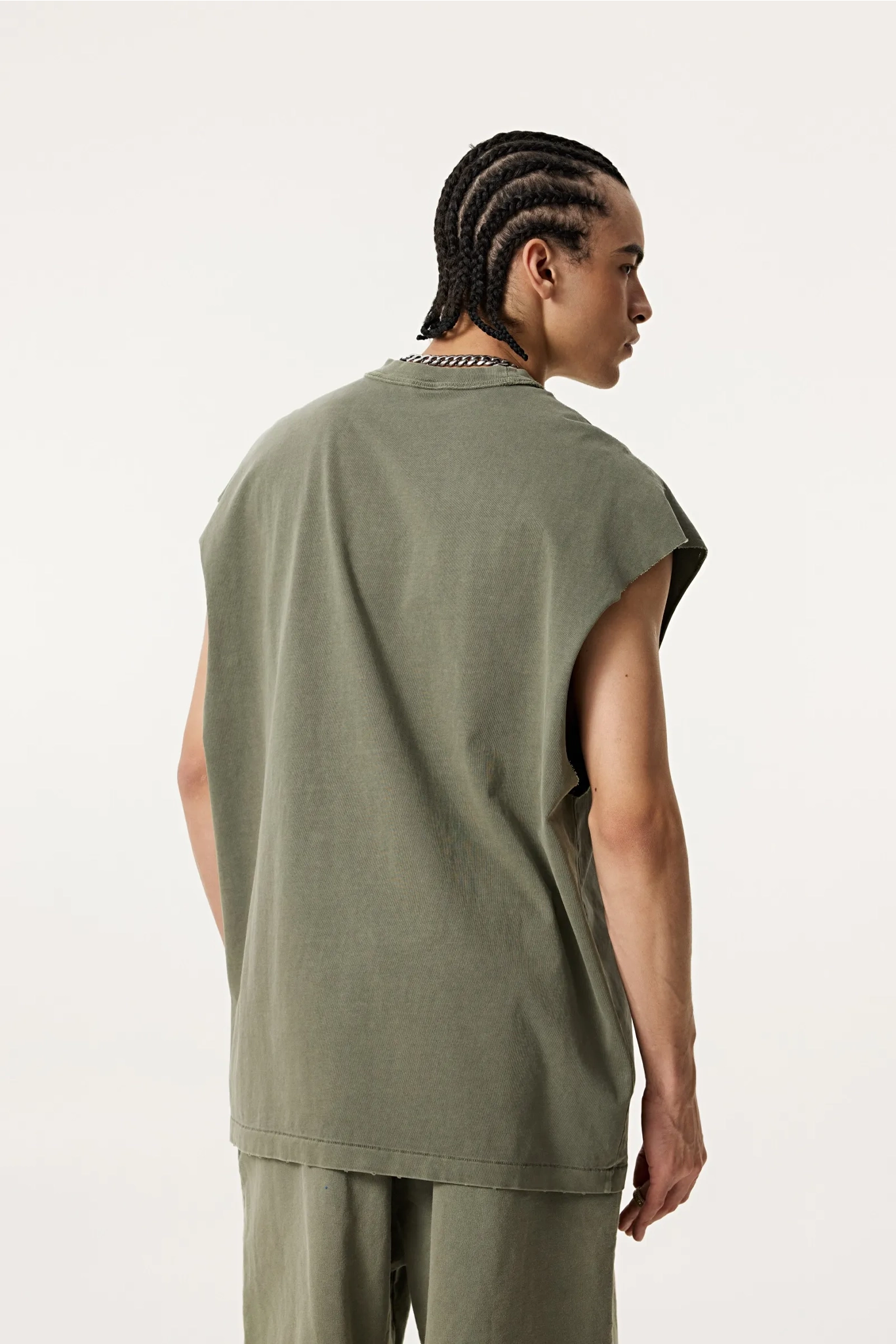 Person wearing a green sleeveless top and pants on a white background