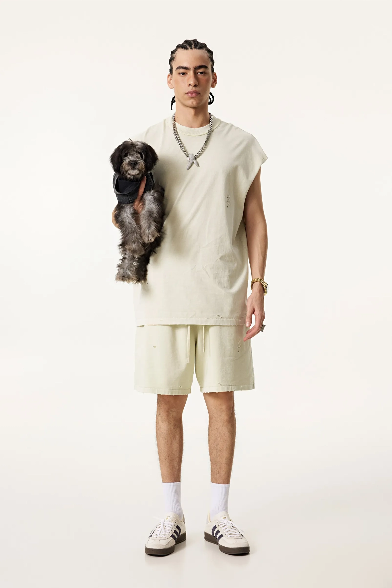 Person wearing a light-colored outfit holding a small dog on a white background