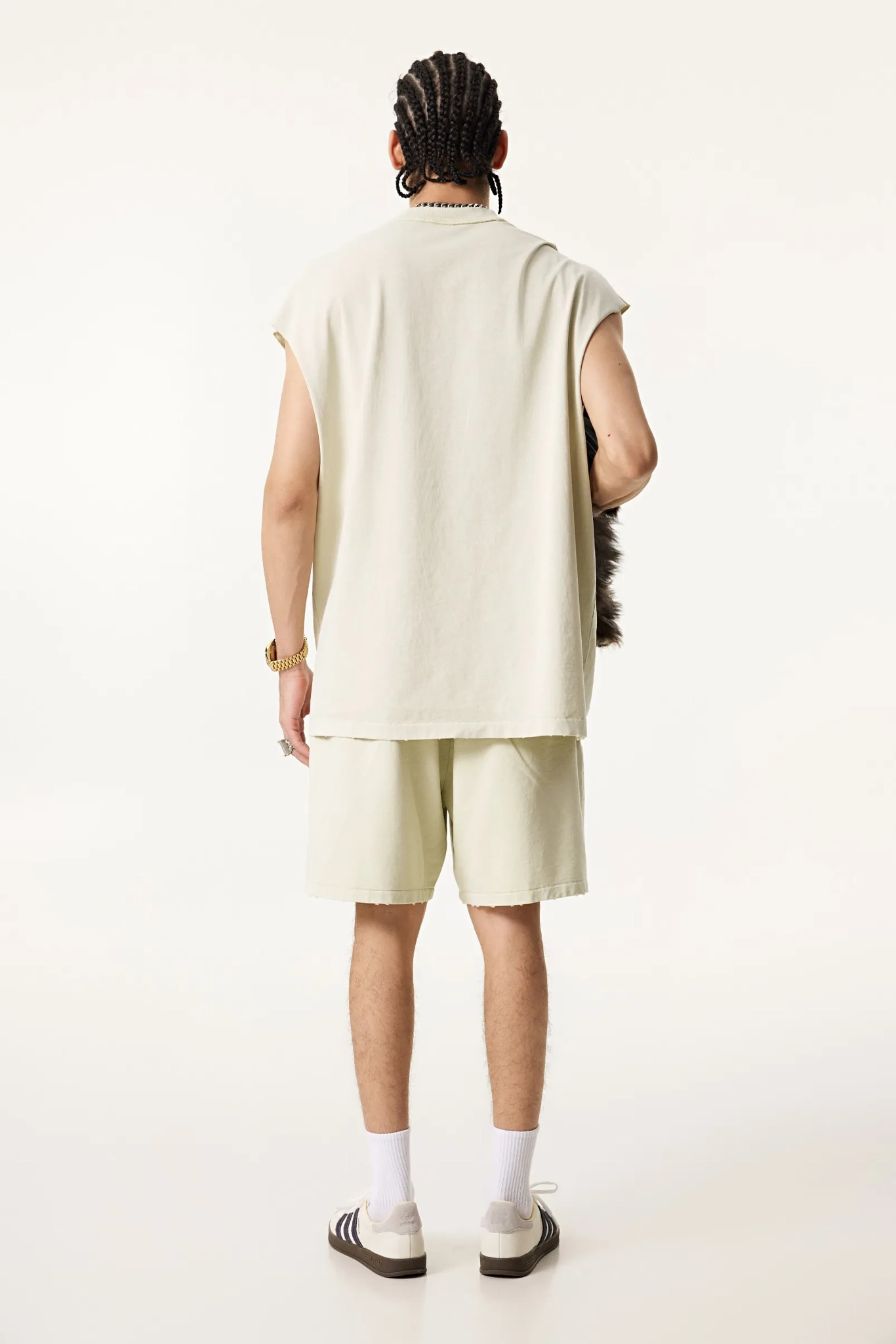 Person wearing a beige sleeveless top and shorts on a white background