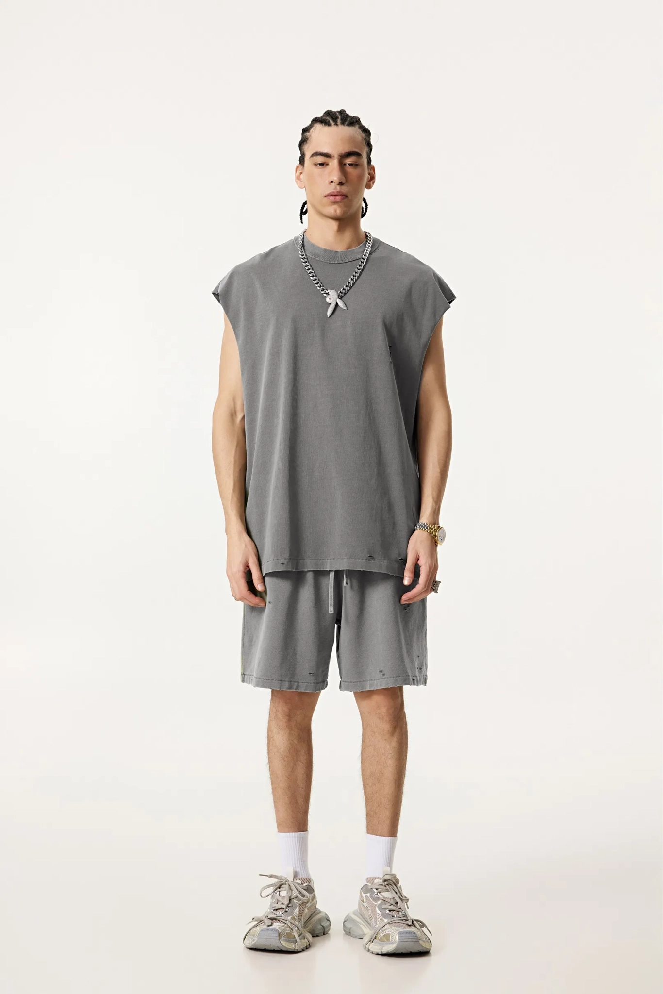 Person wearing a gray sleeveless top and shorts set on a white background