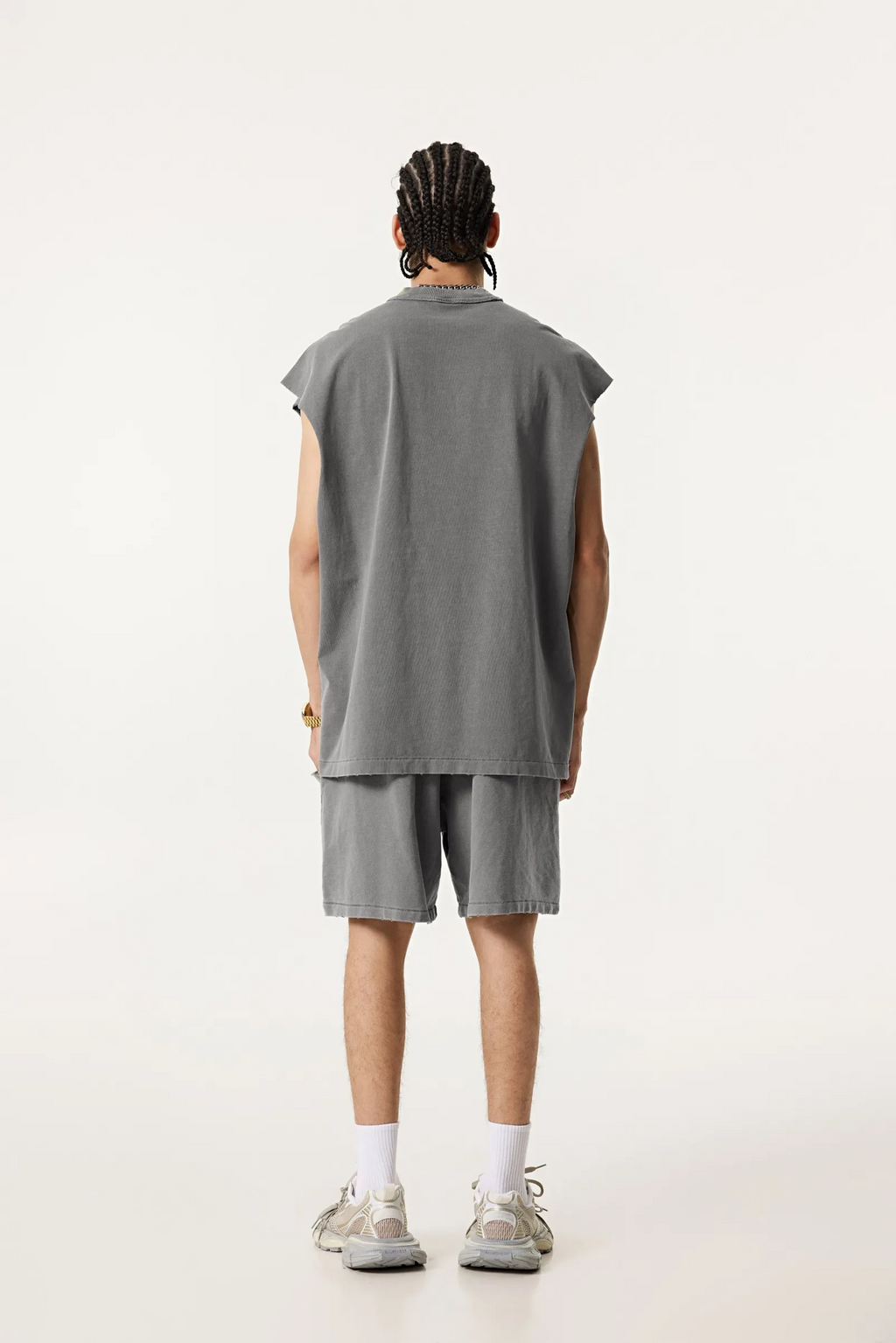 Person wearing a gray sleeveless shirt and shorts set on a white background