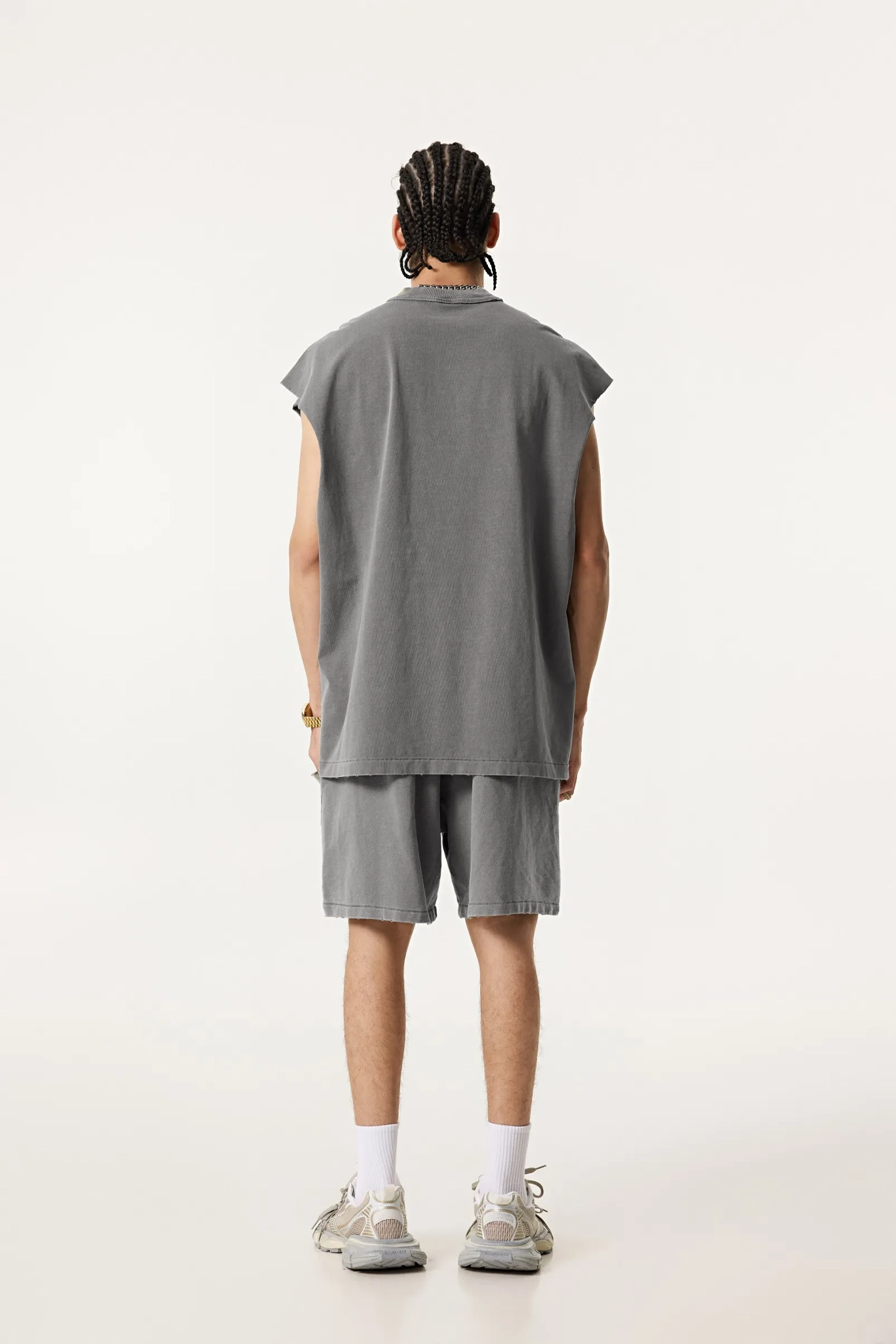 Person wearing a gray sleeveless shirt and shorts set on a white background