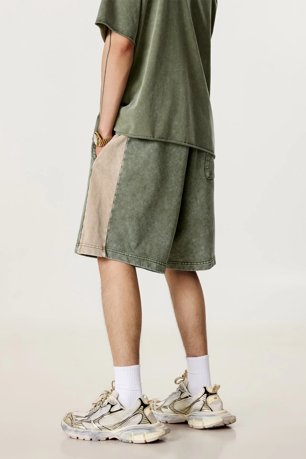 Person wearing a green outfit with beige shorts on a plain background