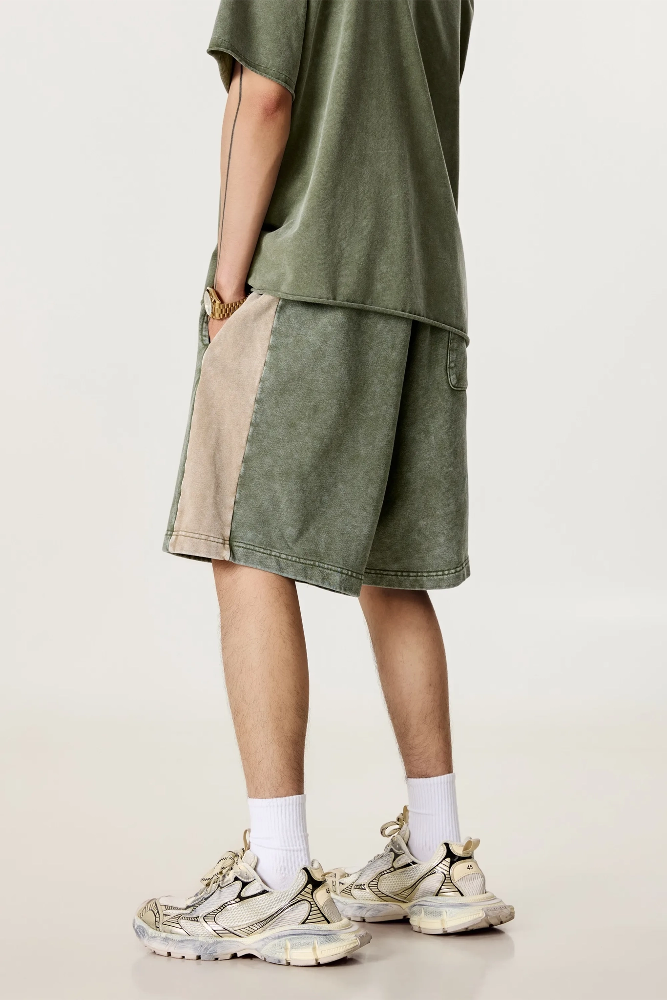 Person wearing a green outfit with beige shorts on a plain background