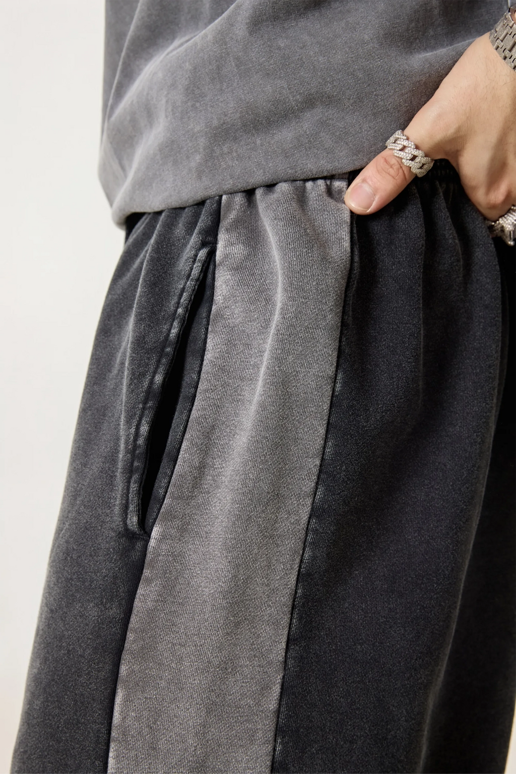 Gray pants with drawstring waist and a hand adjusting the drawstring on a light background