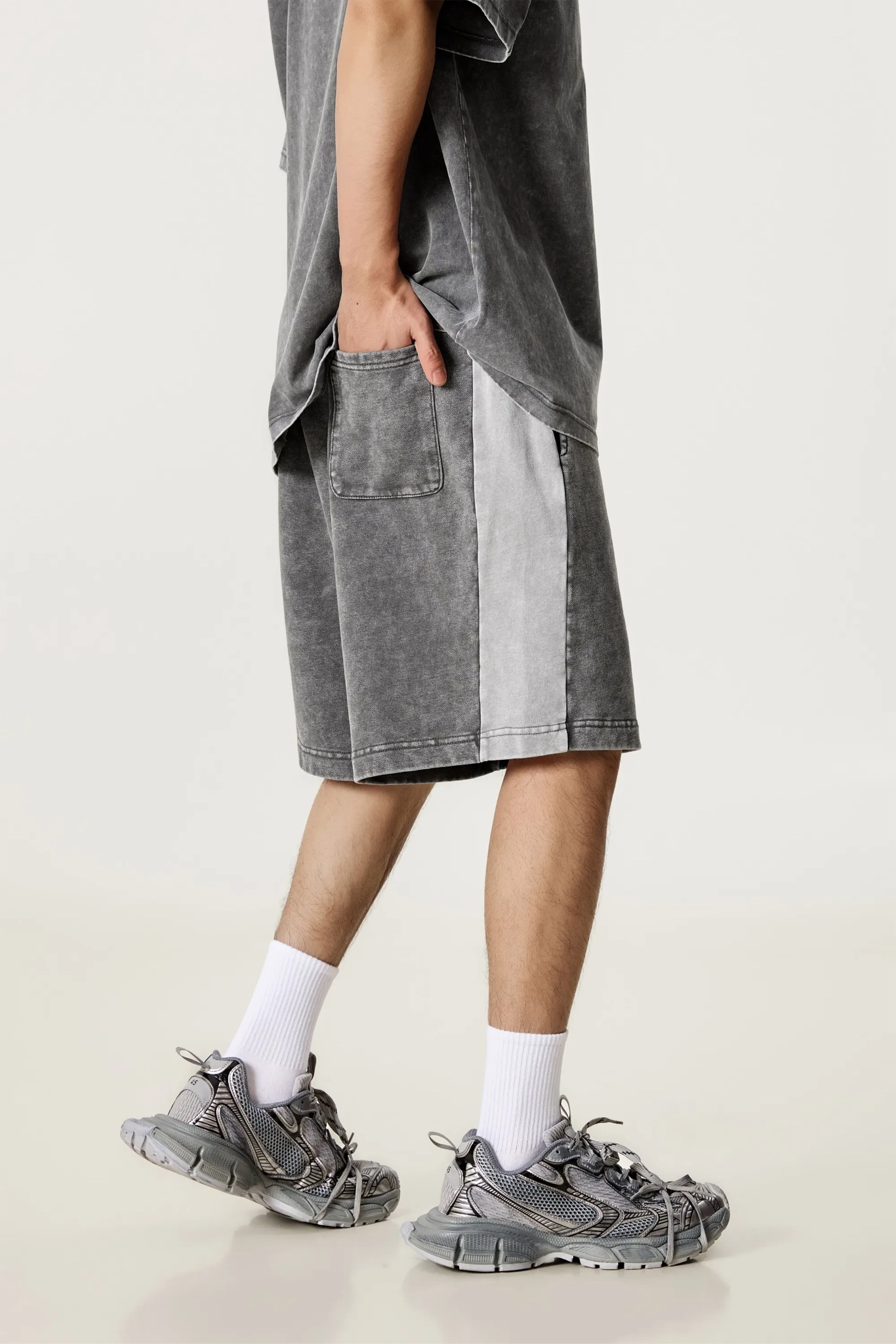 Person wearing gray shorts, white socks, and gray sneakers on a light background