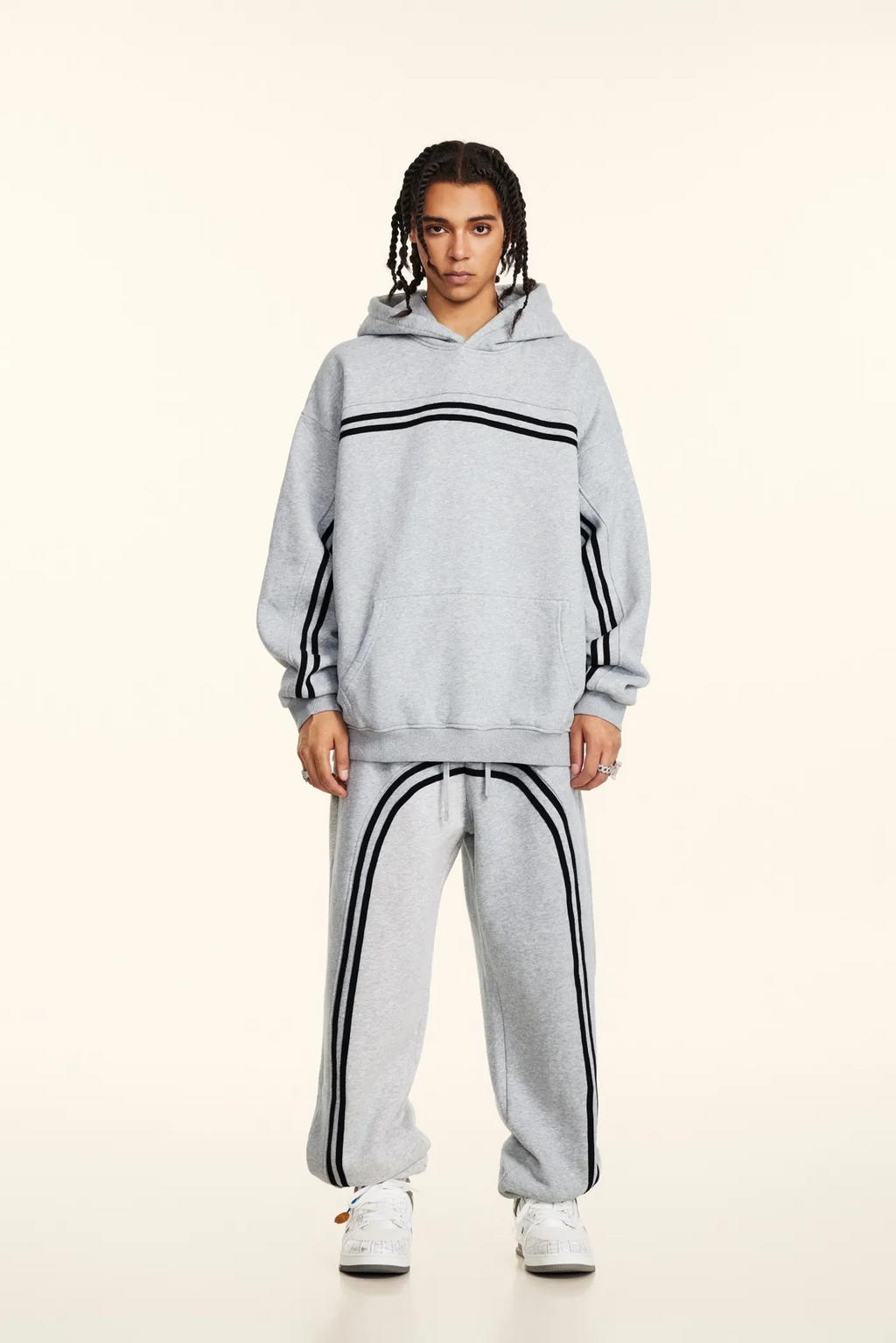 Person wearing a gray tracksuit with black stripes on a white background