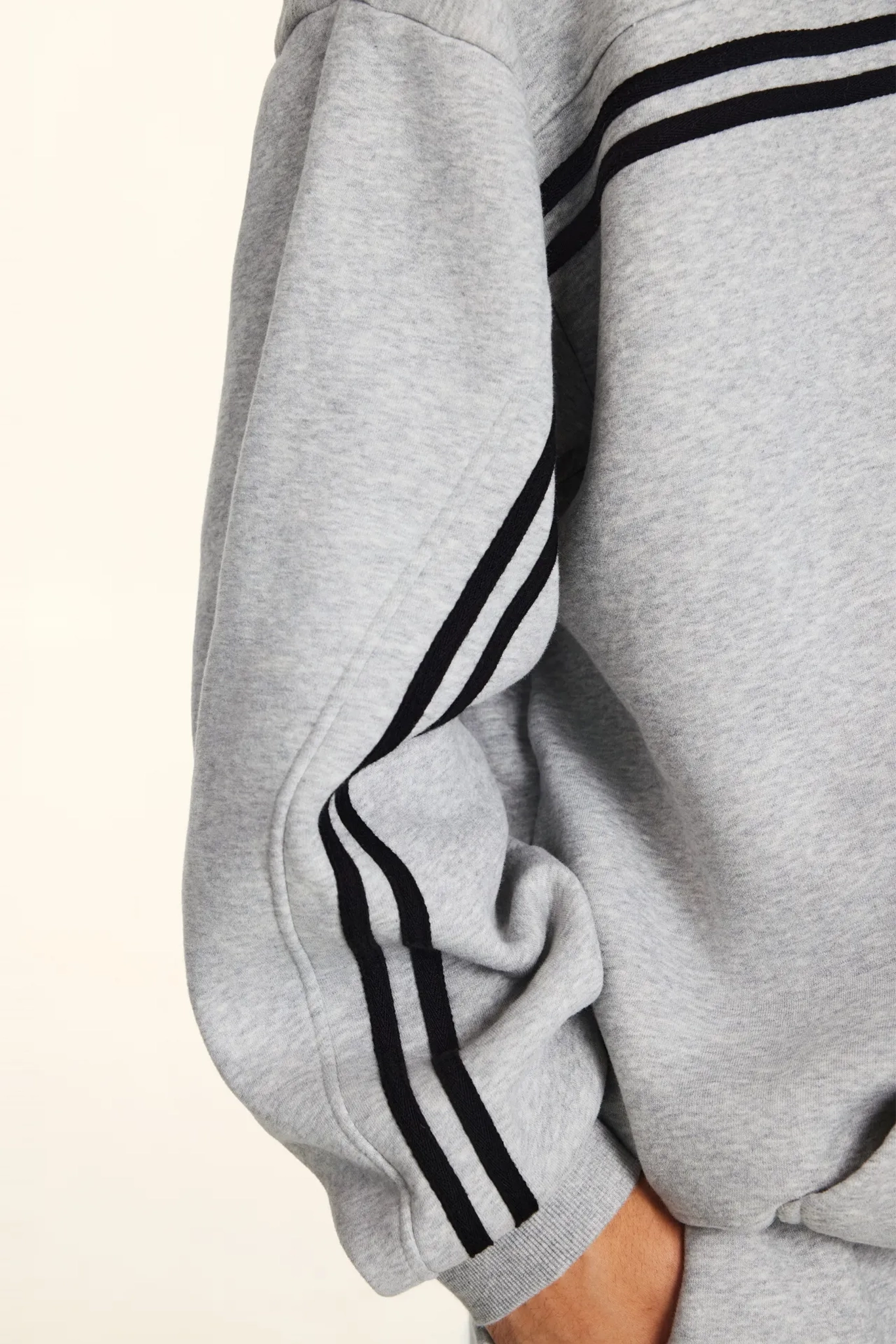 Gray sweatshirt with black stripes on sleeves against a light background