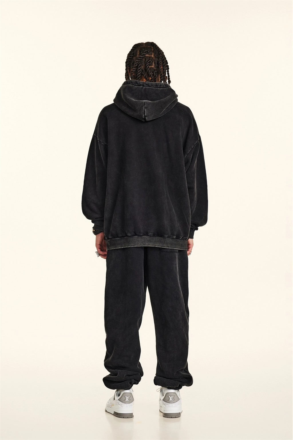 Person wearing a black hoodie and pants on a white background