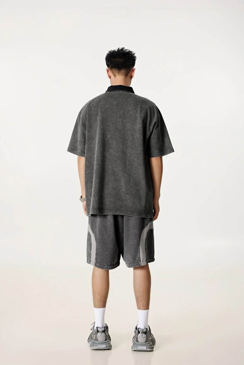 Person wearing a gray polo shirt and shorts set on a white background