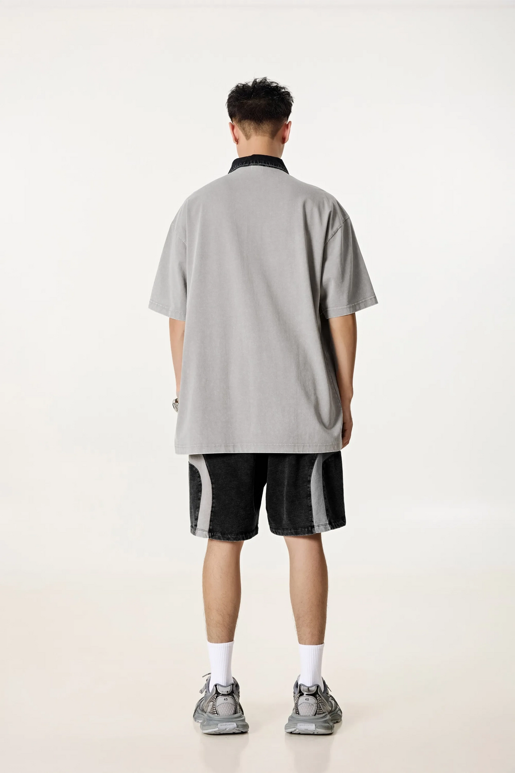 Person wearing a gray oversized t-shirt and black shorts on a white background