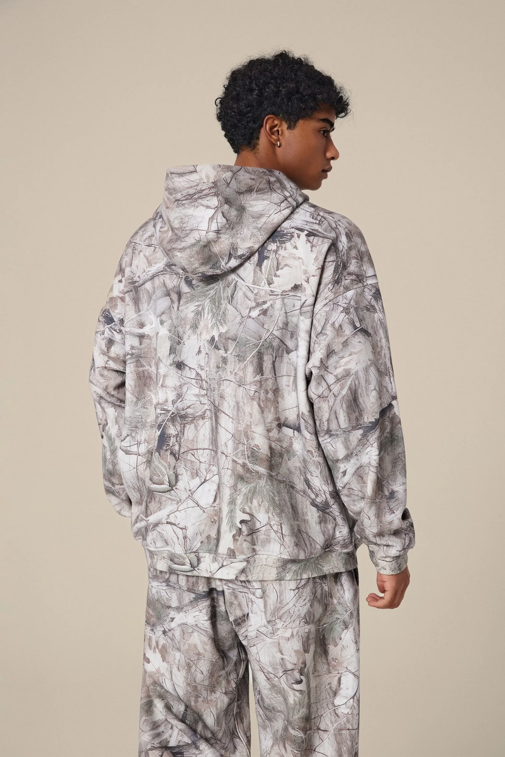 Person wearing a camouflage outfit on a beige background