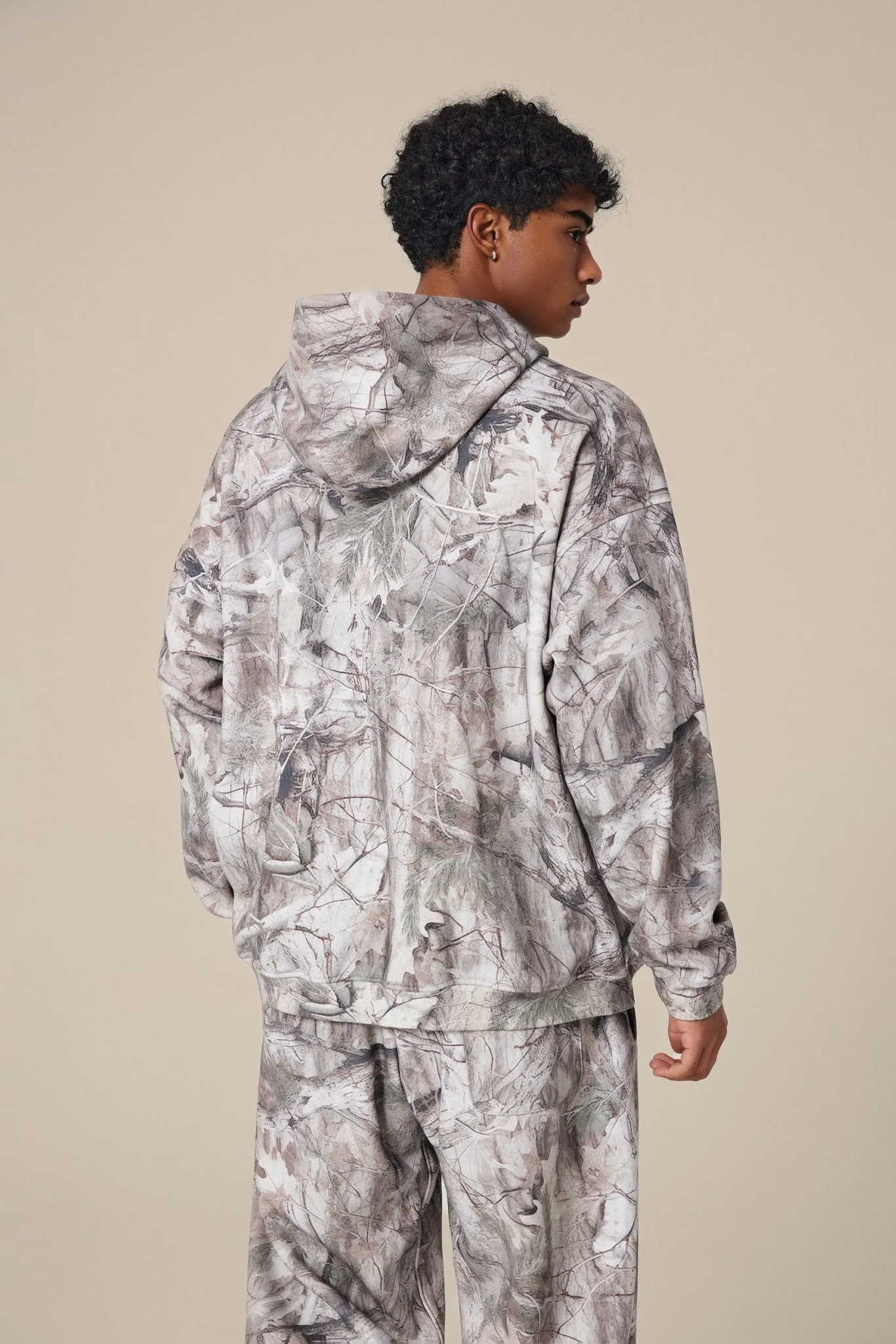 Person wearing a camouflage outfit on a beige background