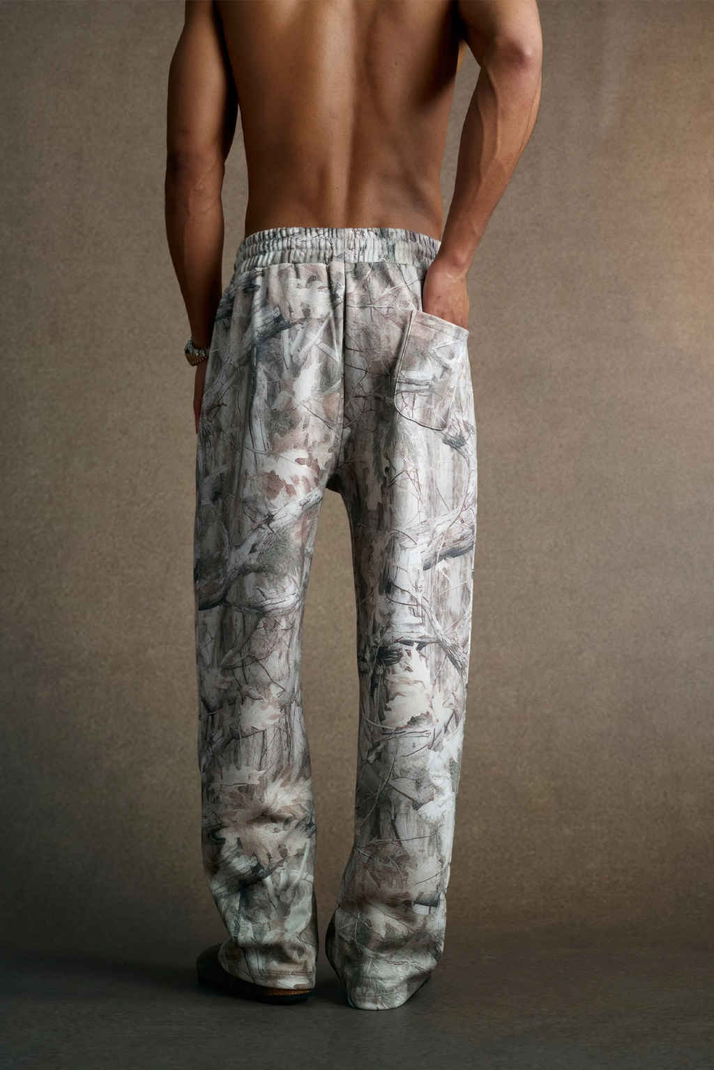 Person wearing camouflage pants against a brown background