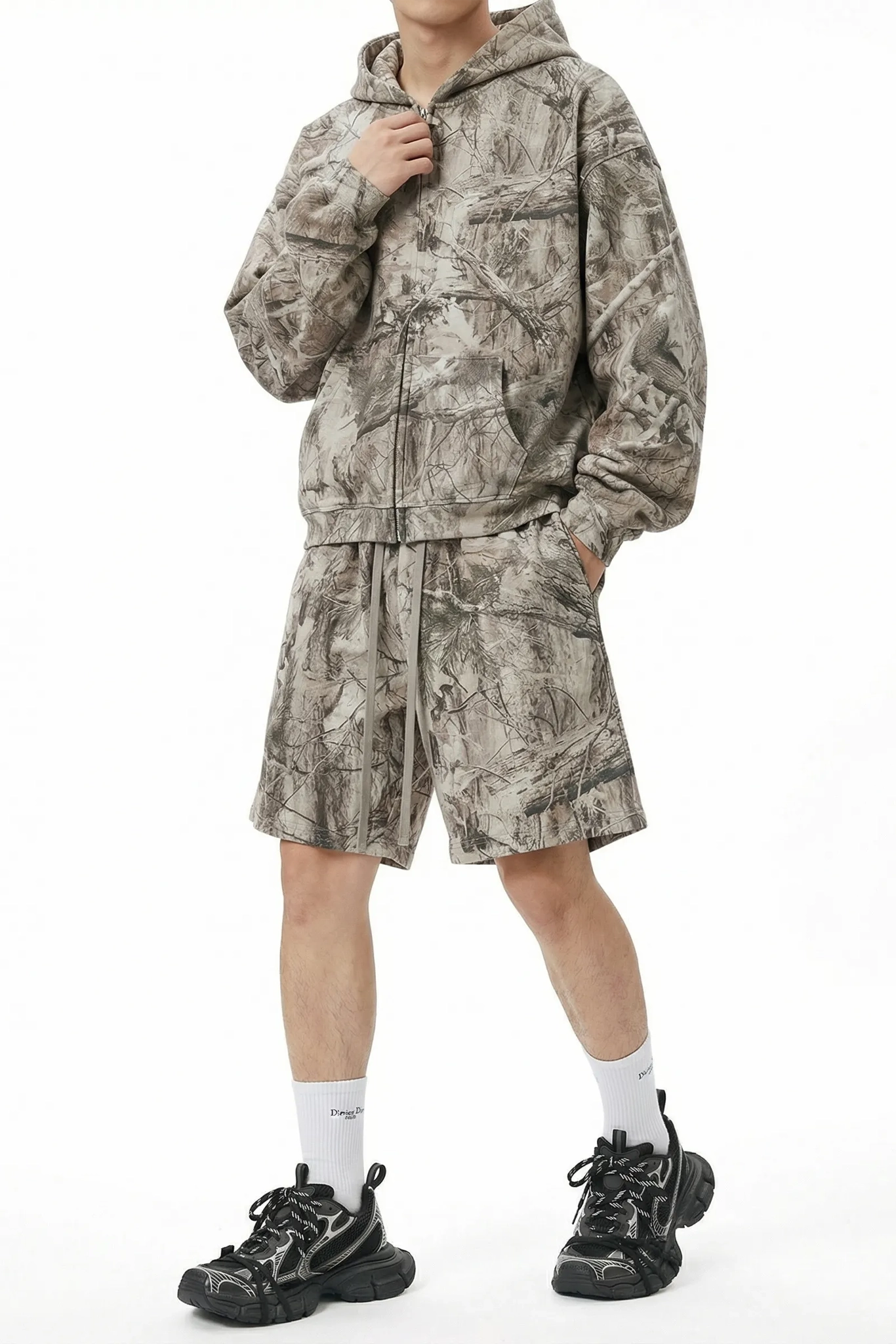 Person wearing a camouflage tracksuit with shorts on a white background