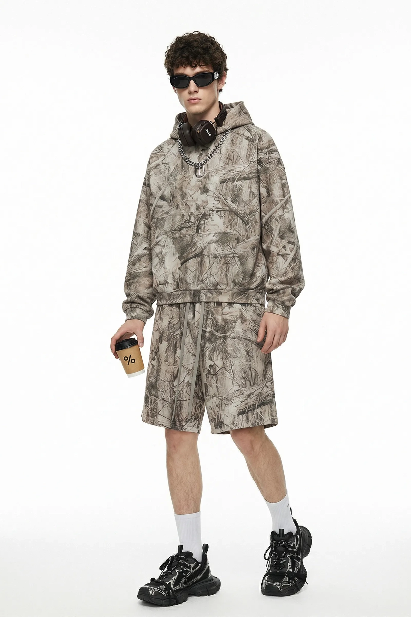 Person wearing a camouflage outfit with a hoodie and shorts on a white background